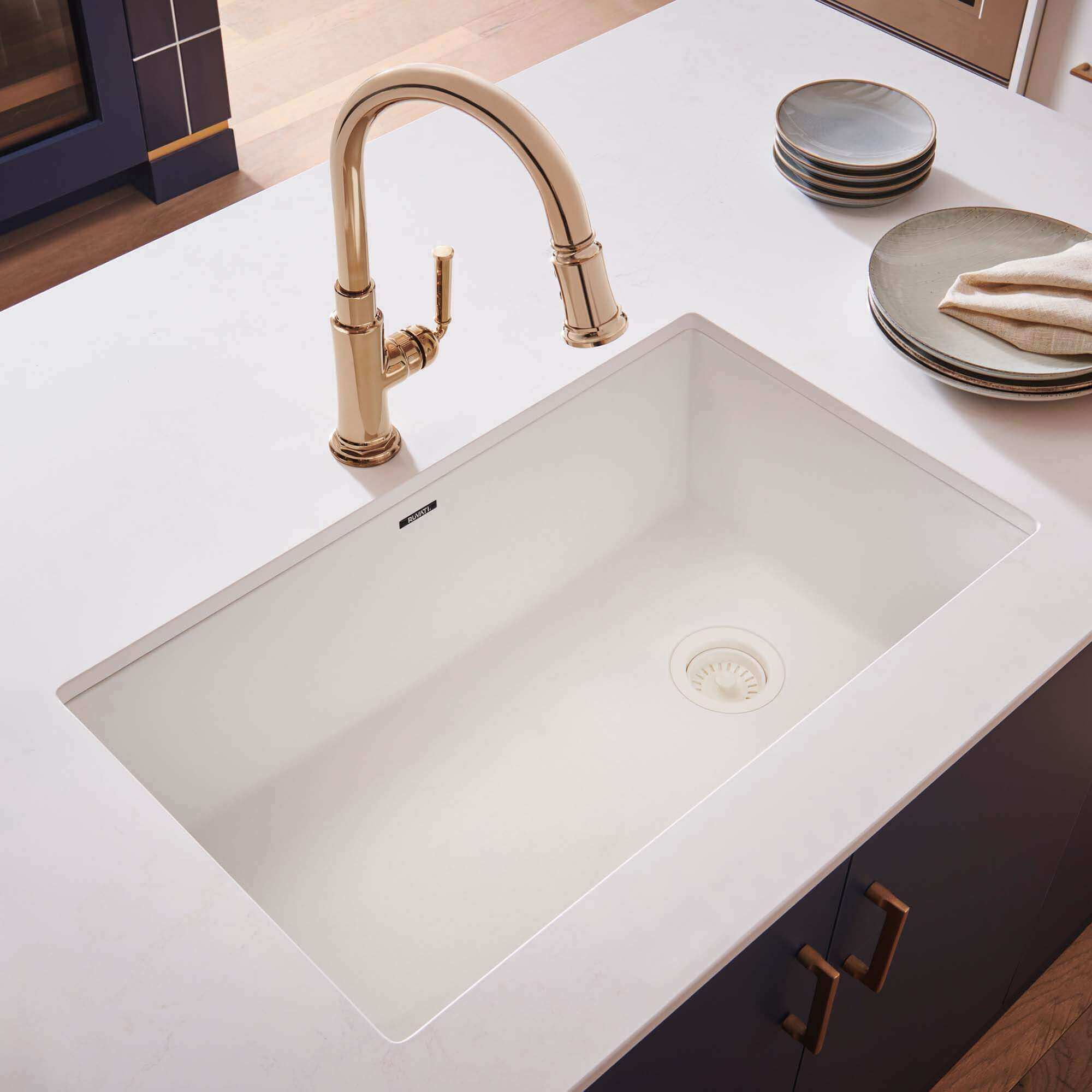 Ruvati 32" epiGranite undermount kitchen sink in white with gold faucet on a white countertop