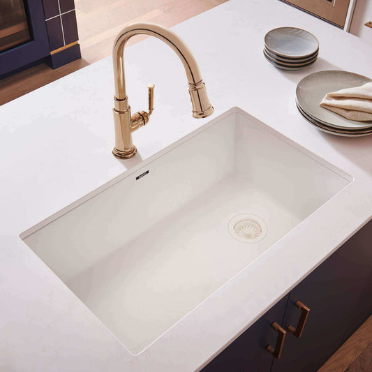 Ruvati 32" epiGranite undermount kitchen sink in white with gold faucet on a white countertop