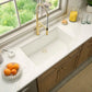 Ruvati 32" undermount epiGranit kitchen sink in marble countertop, with wooden cabinets.