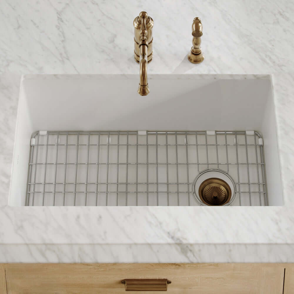 Whitehaus dual mount offset drain fireclay kitchen kitchen sink with gold faucet and drain on a marble countertop