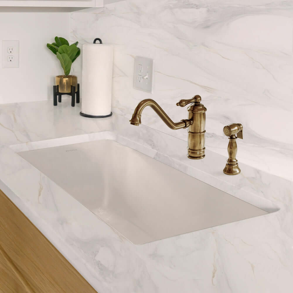 Whitehaus 34" dual mount fireclay kitchen sink with brass faucet and handles on a marble countertop.