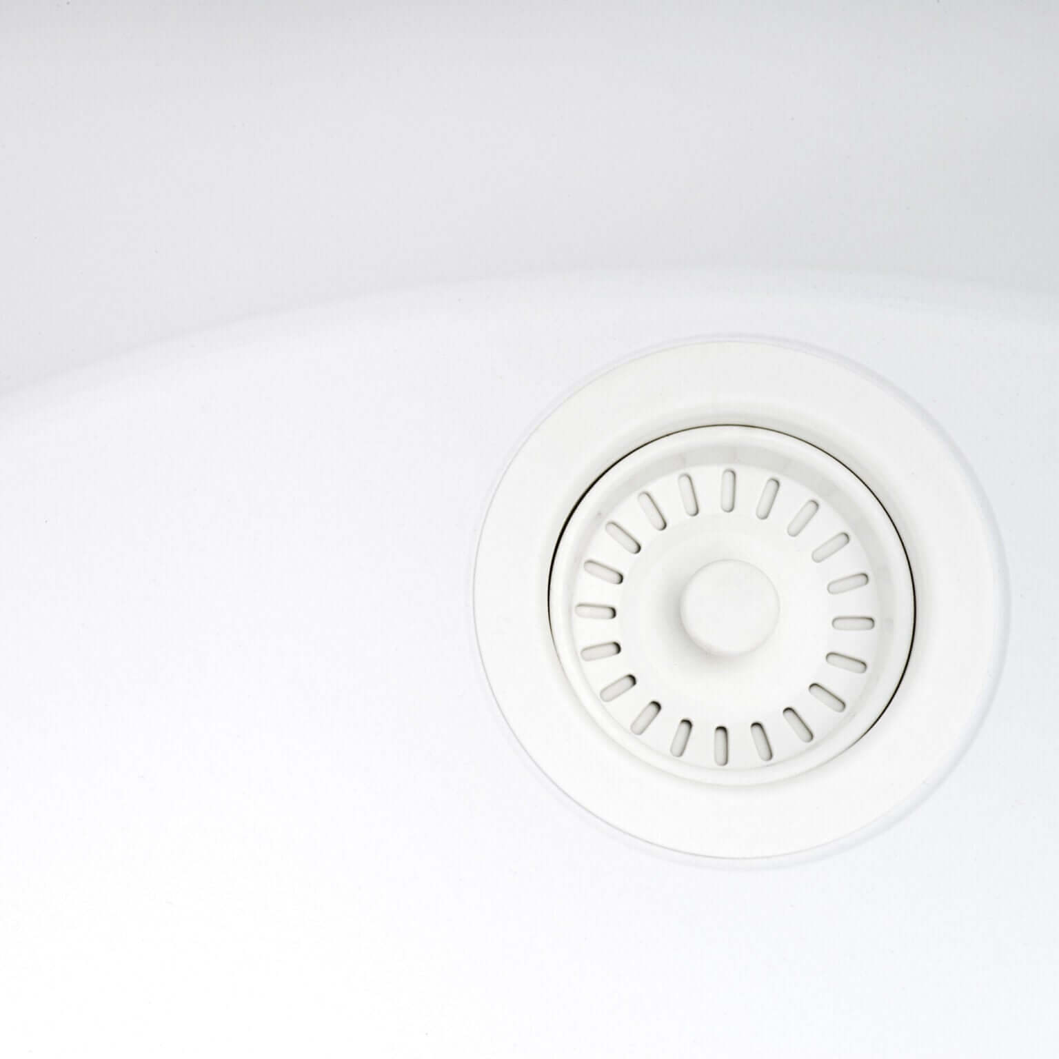 Close-up of a white kitchen sink drain in a Ruvati undermount sink.
