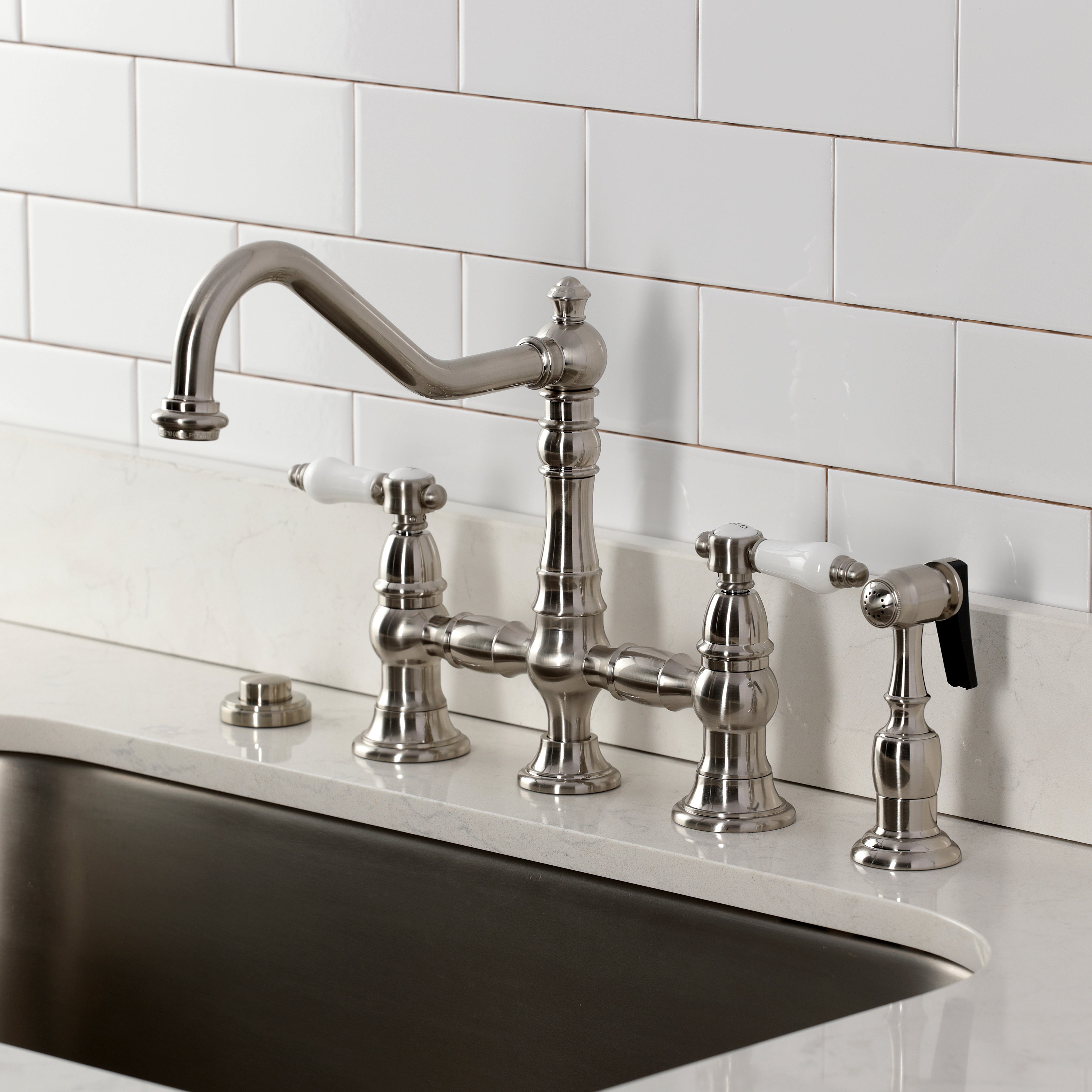 Kingston KS3277BPLBS Bel-Air Bridge Kitchen Faucet with Brass Sprayer, Brushed Brass on a kitchen sink.
