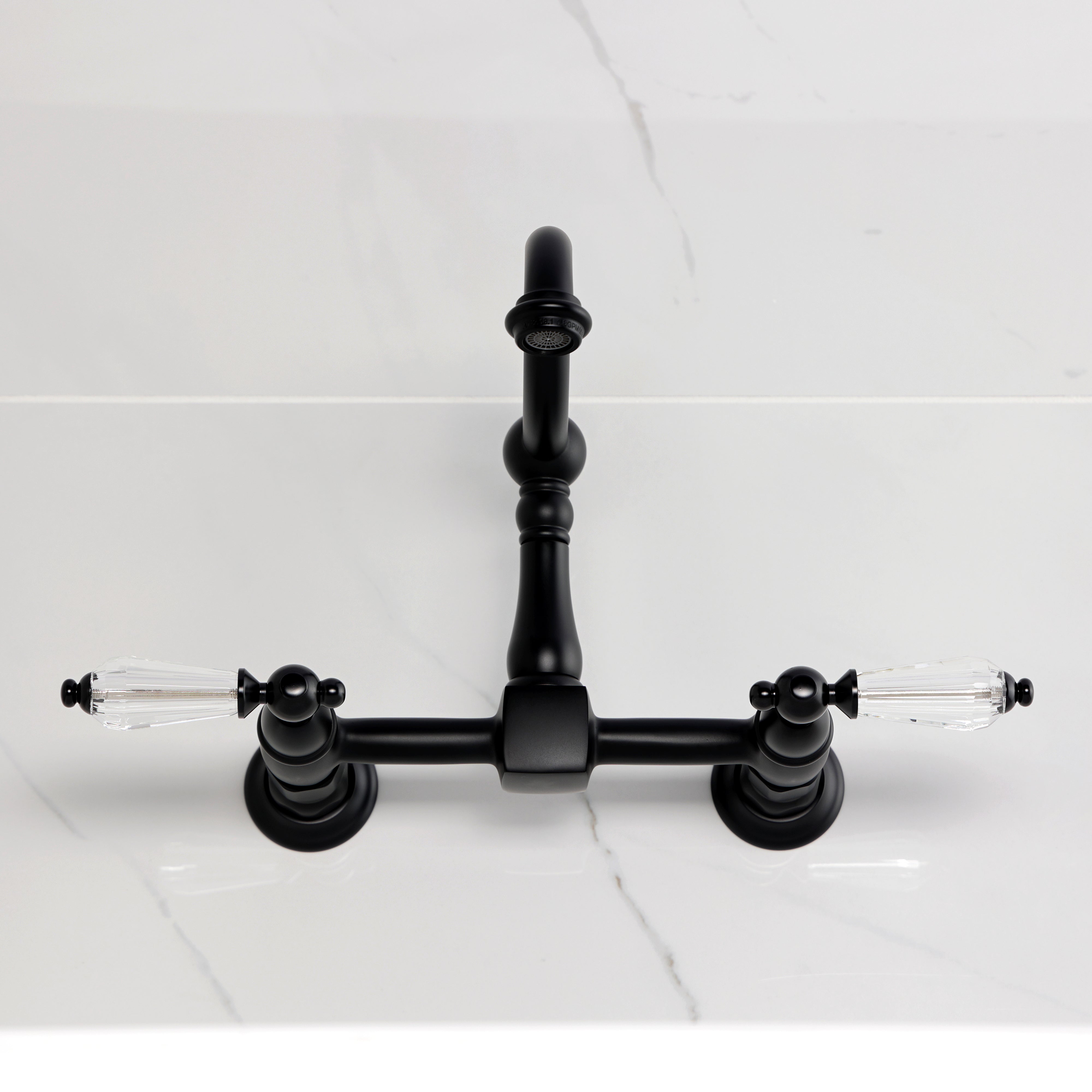 Kingston KS1263WLL Willshire Two-Handle Wall Mount Bridge Kitchen Faucet, Antique Brass on a marble countertop.
