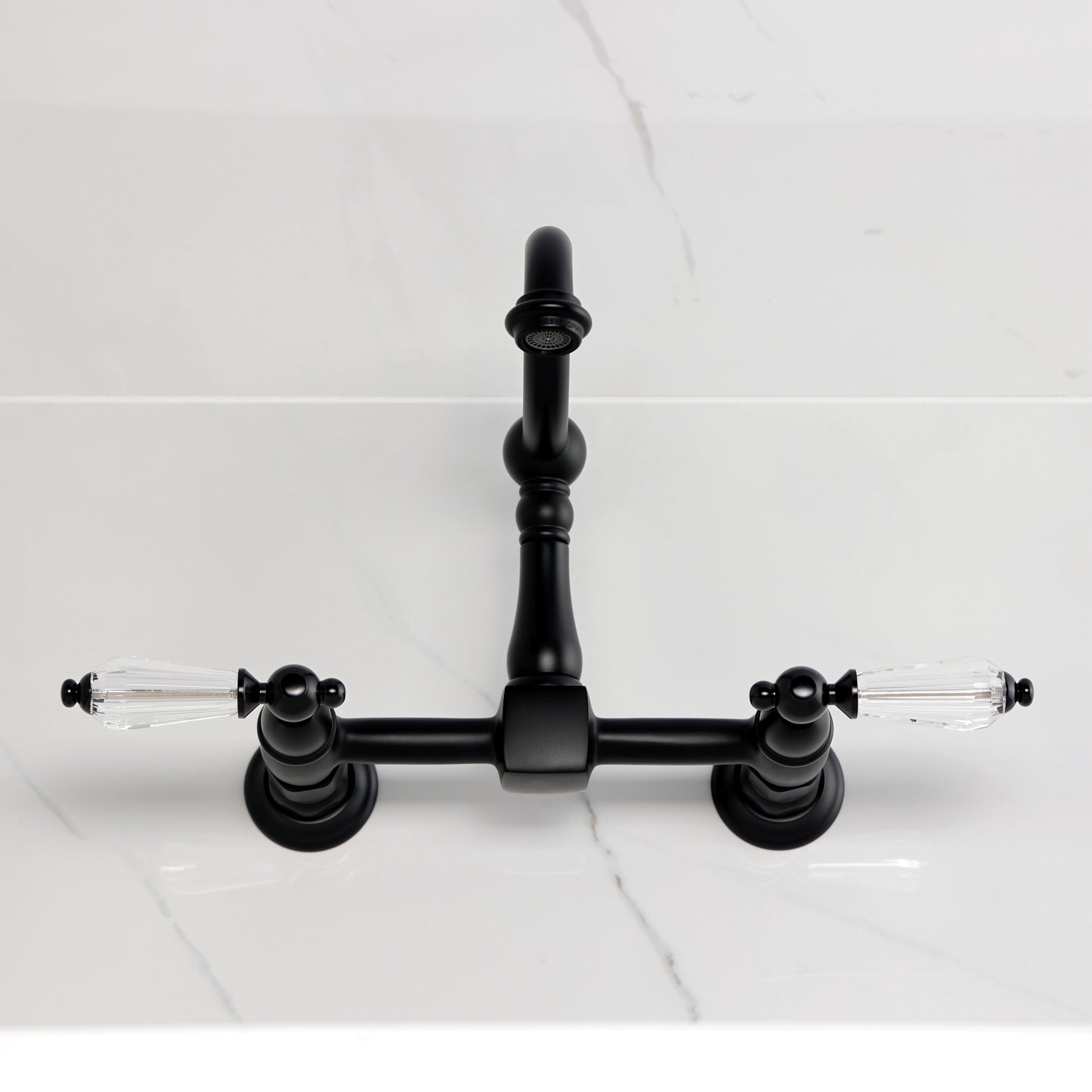 Kingston KS1263WLL Willshire Two-Handle Wall Mount Bridge Kitchen Faucet, Antique Brass on a marble countertop.