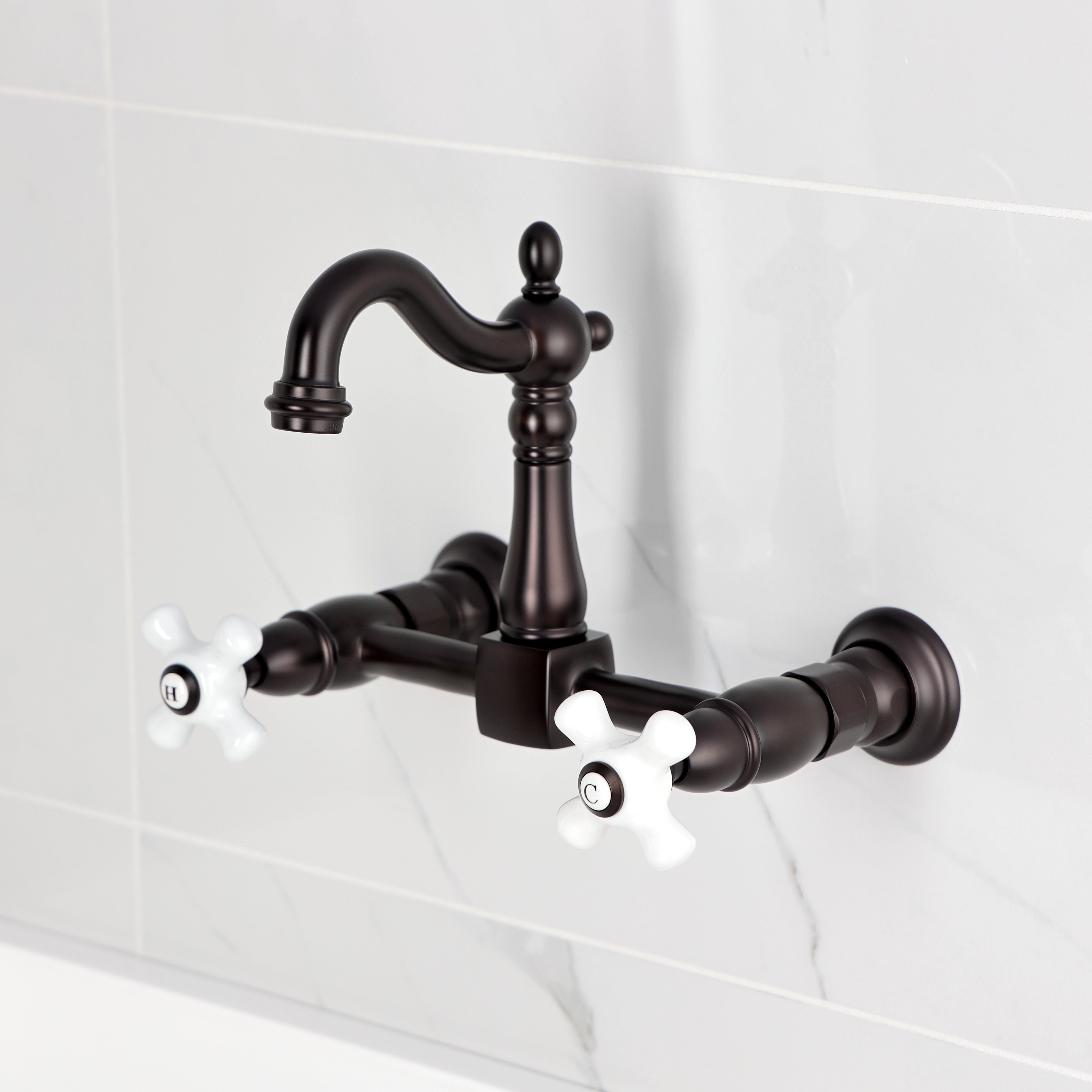 Kingston KS2443PX Heritage Two-Handle Wall Mount Bridge Kitchen Faucet, Antique Brass with Victorian spout and porcelain handles.
