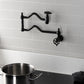 Kingston Brass KS2107CG Fuller Wall Mount Pot Filler Faucet, Brushed Brass against a gray tiled wall with a pot.