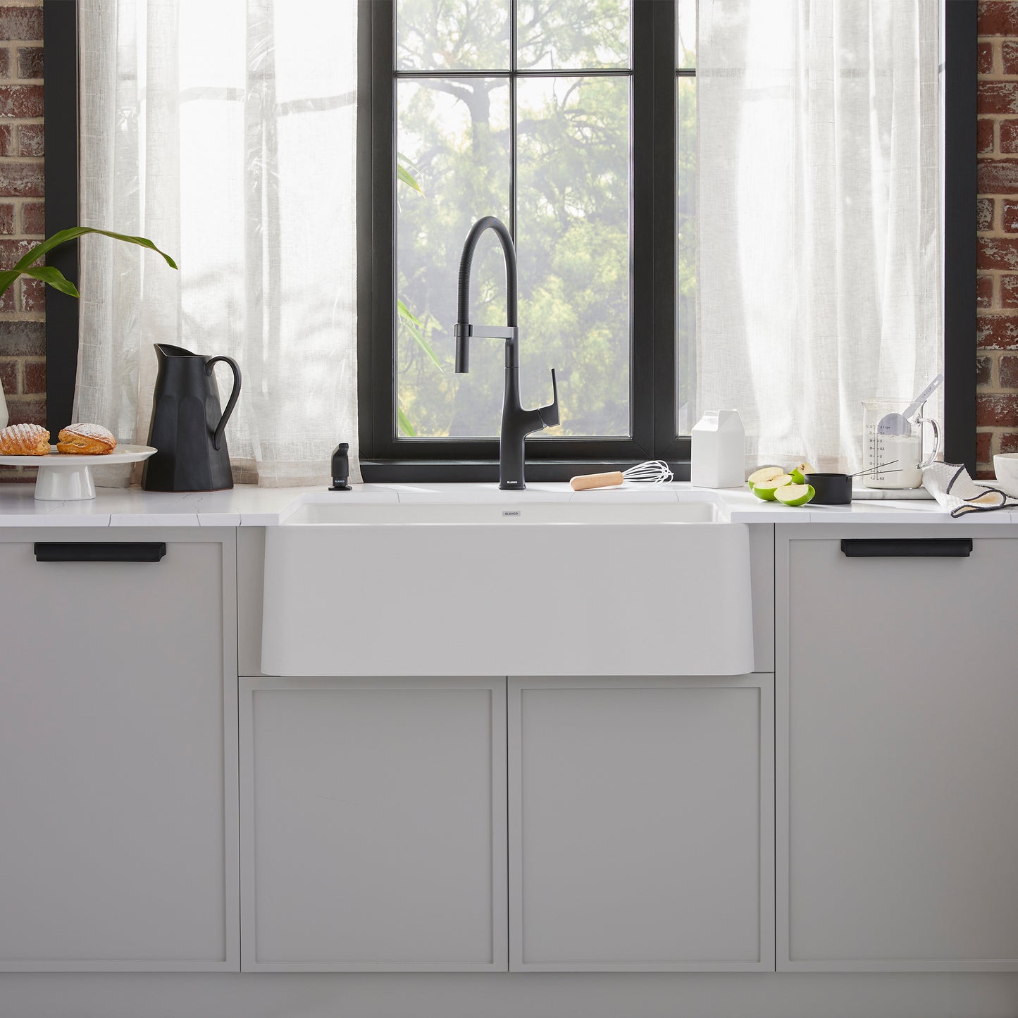 BLANCO Ikon SILGRANIT 30" Single Bowl Apron-Front Farmhouse Sink in modern kitchen with window and countertop.