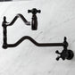 Kingston Brass KS2107PKX Duchess Wall Mount Pot Filler Faucet, Brushed Brass, featuring elegant black porcelain handles