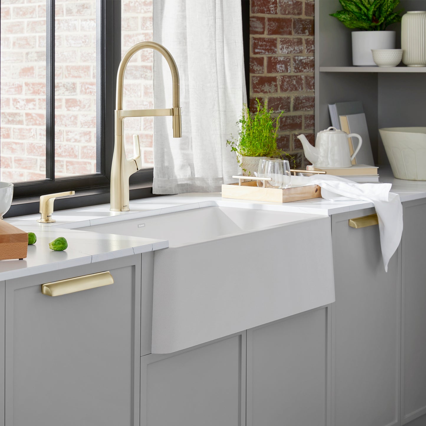 BLANCO Ikon SILGRANIT 30" Single Bowl Apron-Front Farmhouse Sink in a modern kitchen with gold faucet and natural decor.