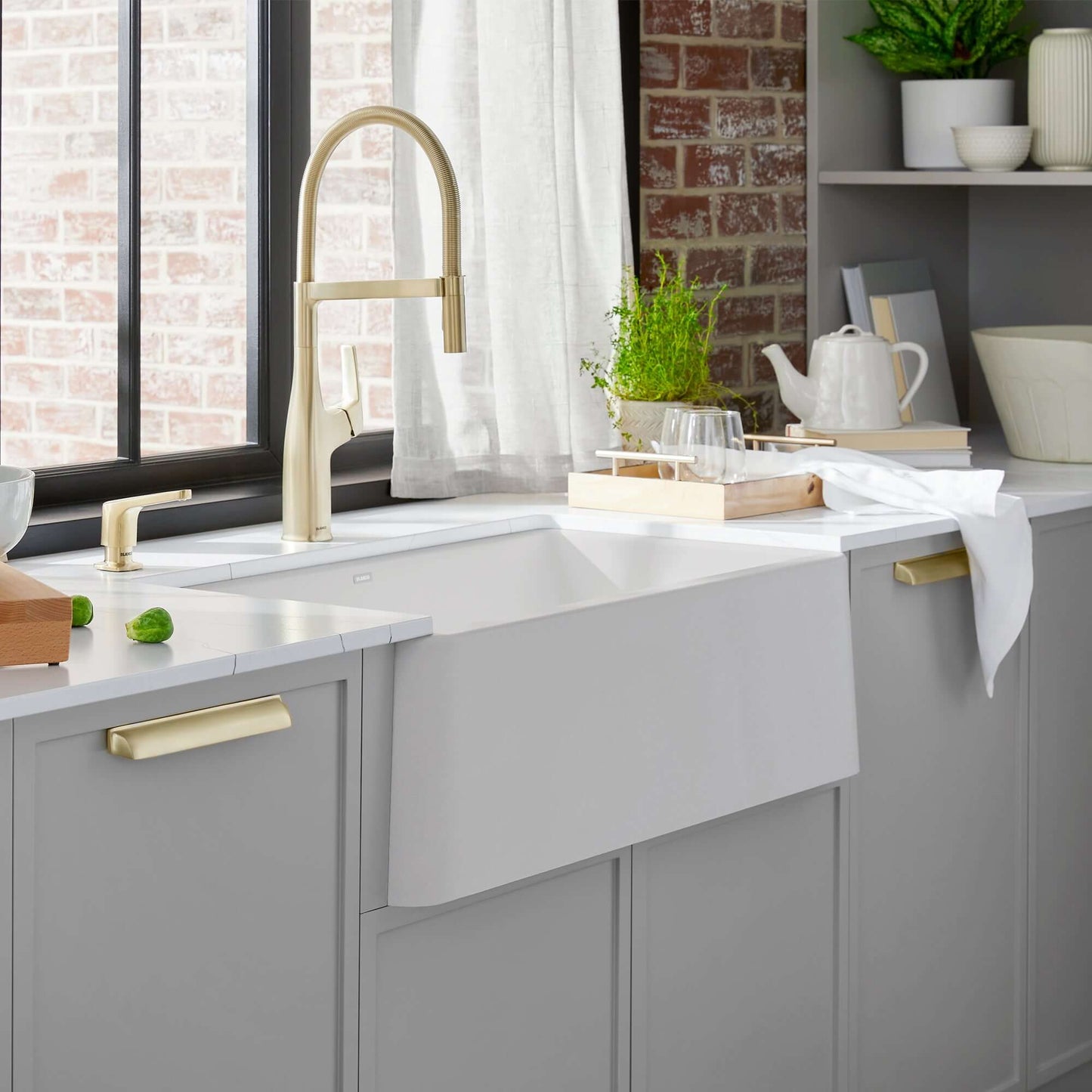 BLANCO Ikon SILGRANIT 33" Single Bowl Apron-Front Farmhouse Sink in modern kitchen setting with gold faucet.