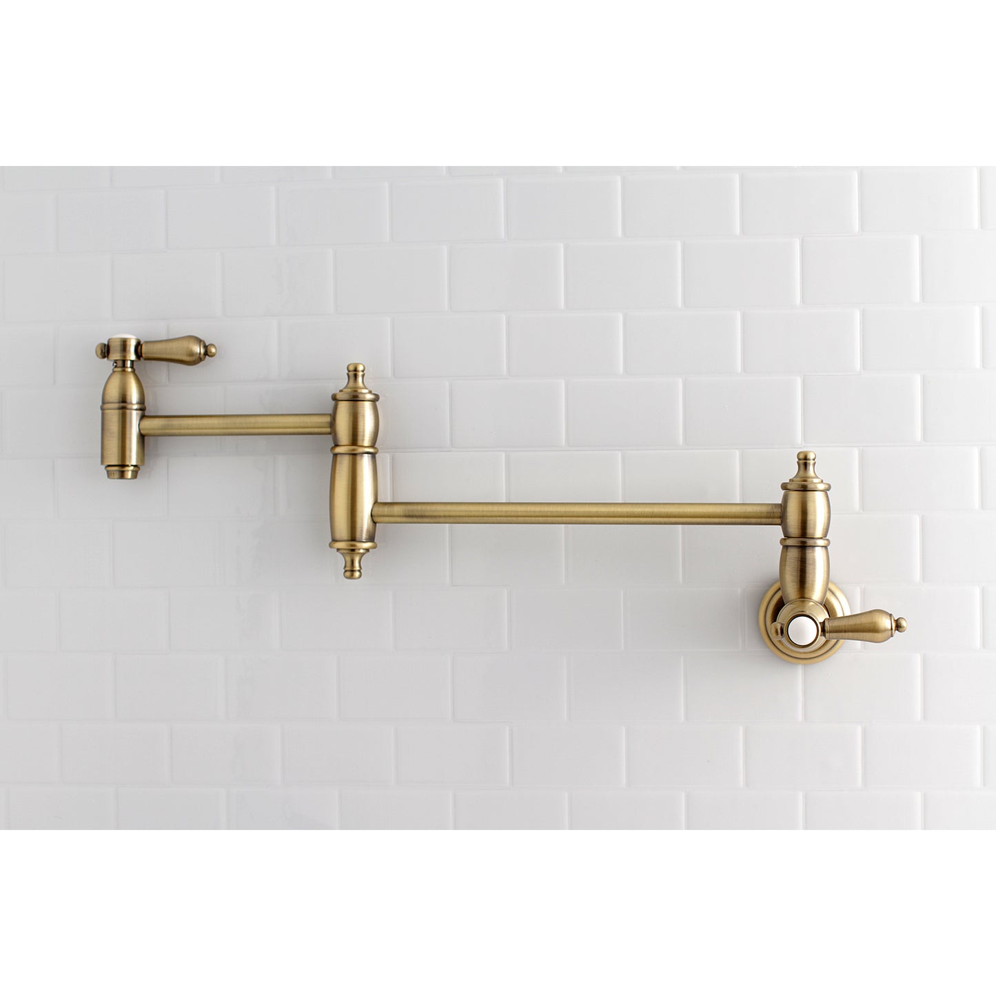 Kingston Brass KS3103BAL Heirloom Wall Mount Pot Filler Faucet, Antique Brass on white backsplash.