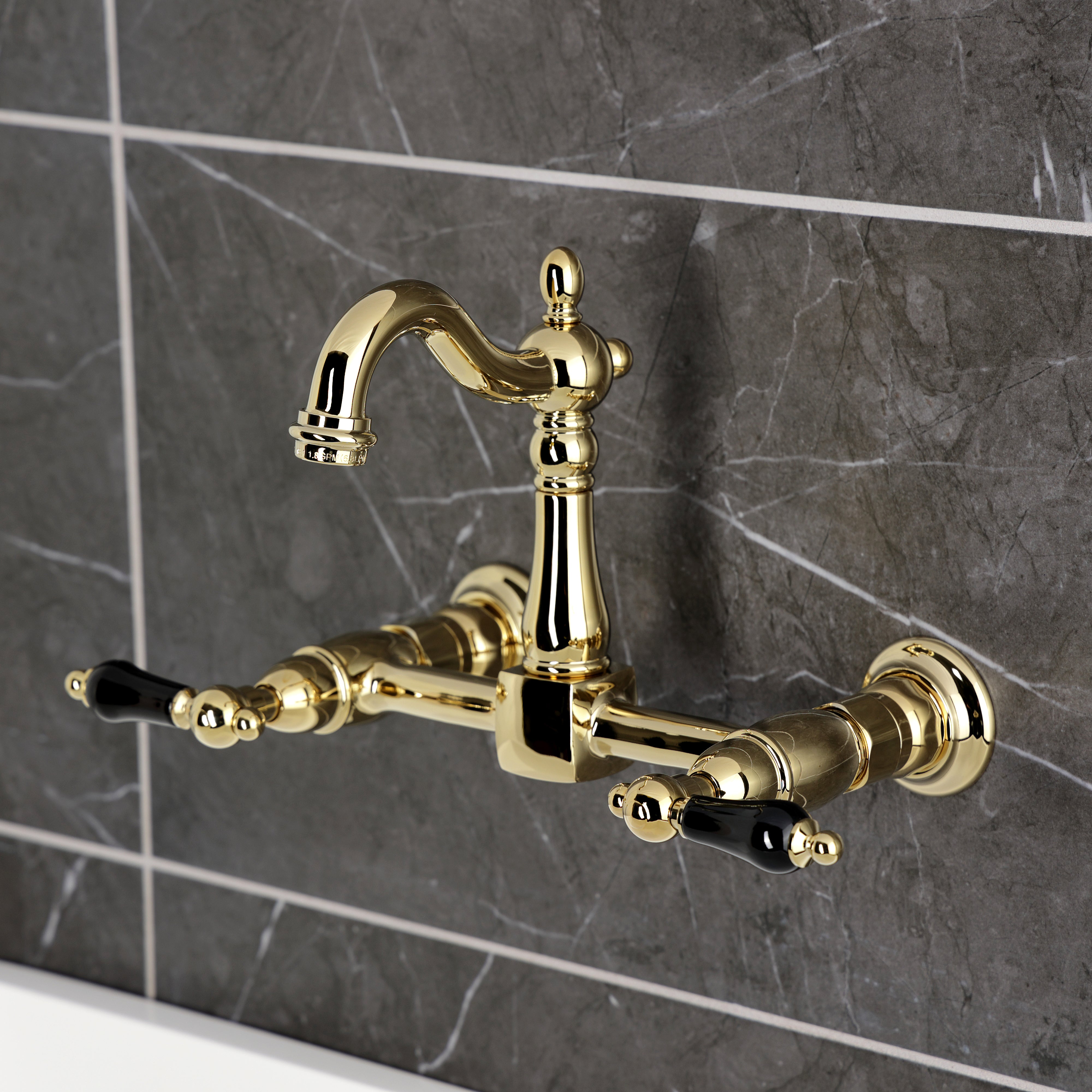 Kingston KS2443PKL Duchess Two-Handle Wall Mount Bridge Kitchen Faucet, Antique Brass on a modern grey tiled wall.