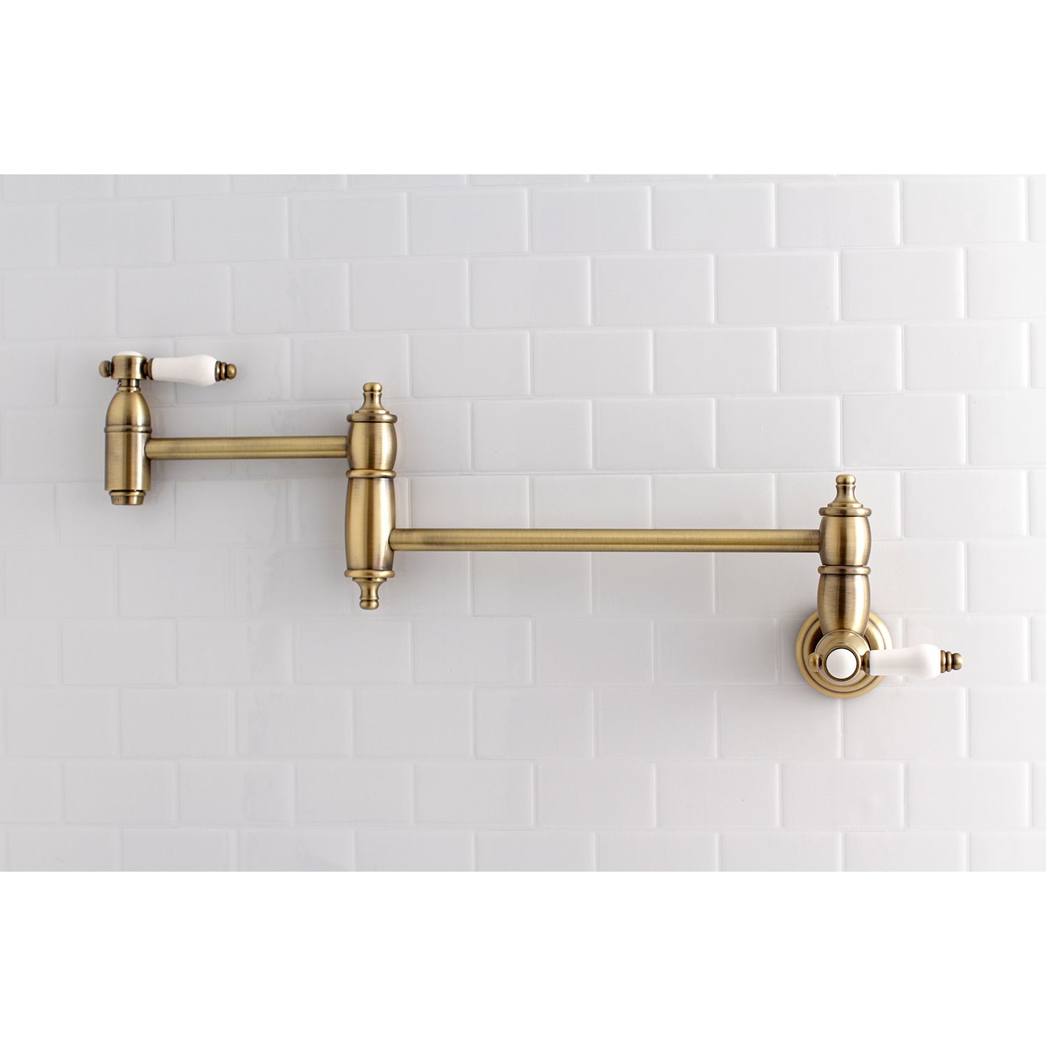 Kingston Brass KS3103BPL Bel-Air Wall Mount Pot Filler Faucet, Antique Brass on a white tiled backdrop.