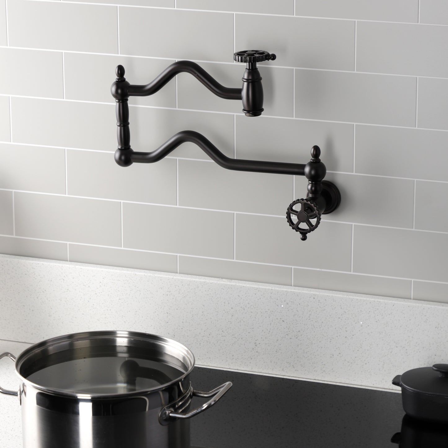 Kingston Brass KS2107CG Fuller Wall Mount Pot Filler Faucet, Brushed Brass mounted with a pot on stove.