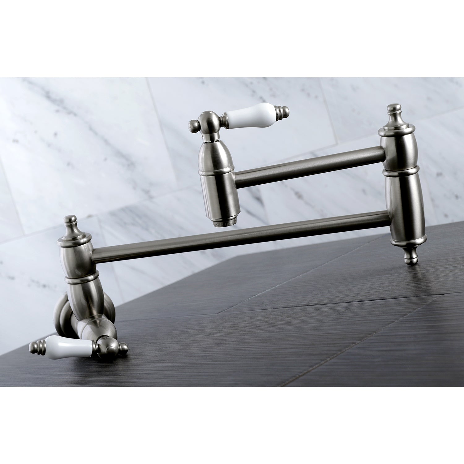 Kingston Brass KS3103PL Restoration Wall Mount Pot Filler Faucet, Antique Brass on a wooden countertop.