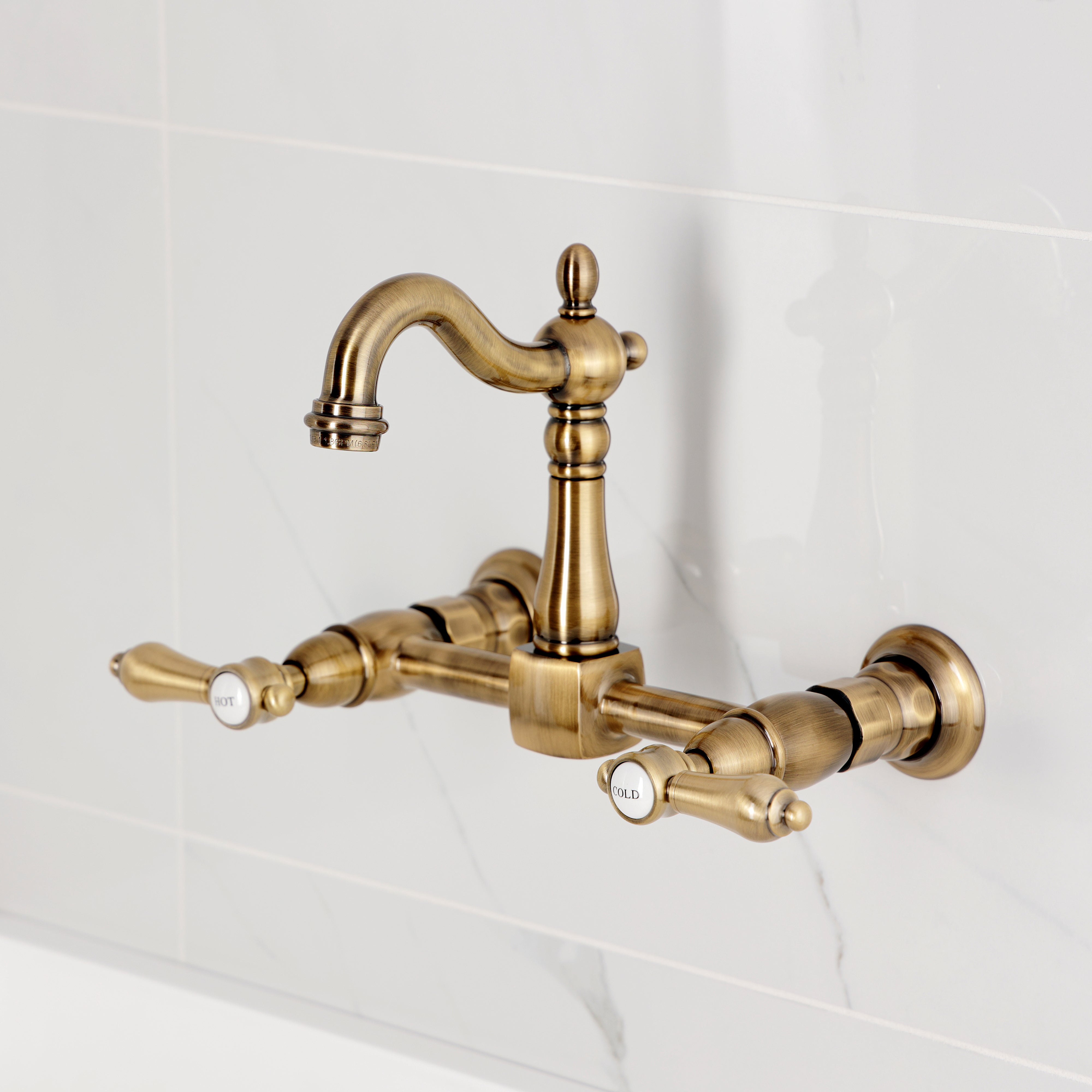 Kingston KS2443BAL Heirloom Two-Handle Wall Mount Bridge Kitchen Faucet, Antique Brass showing hot and cold handles.