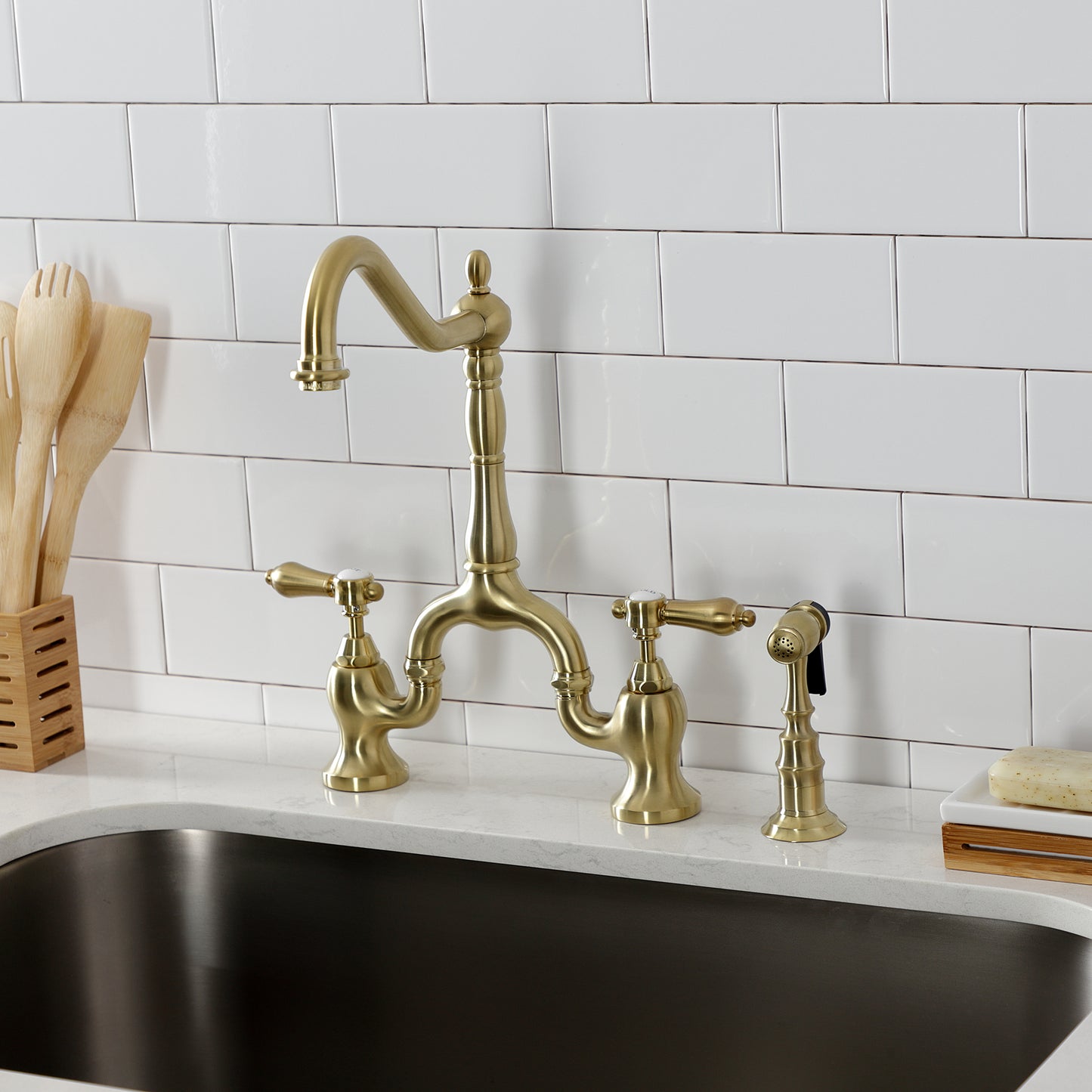 Kingston KS7753BALBS Heirloom Bridge Kitchen Faucet with Brass Sprayer, Antique Brass mounted on modern kitchen sink.