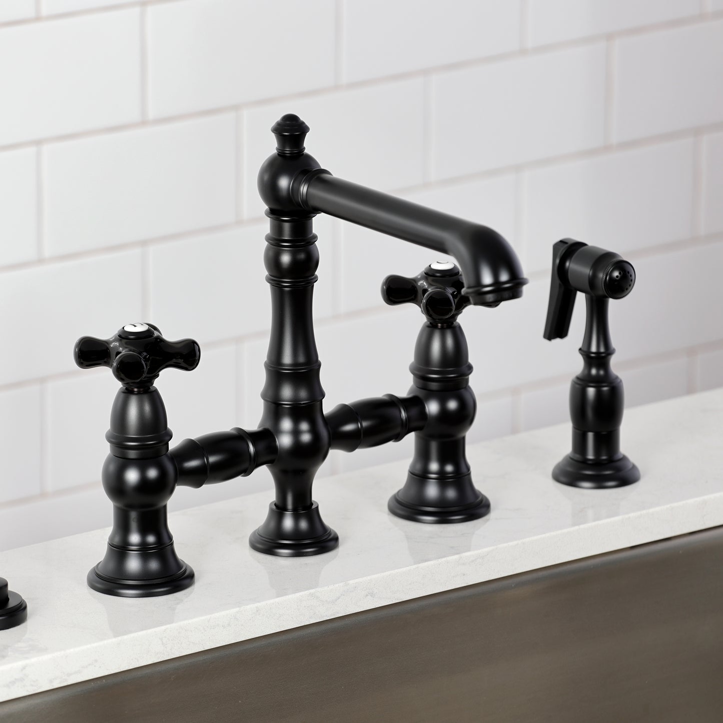 Kingston KS7277PKXBS Duchess Bridge Kitchen Faucet with Brass Sprayer, Brushed Brass featuring black porcelain handles.