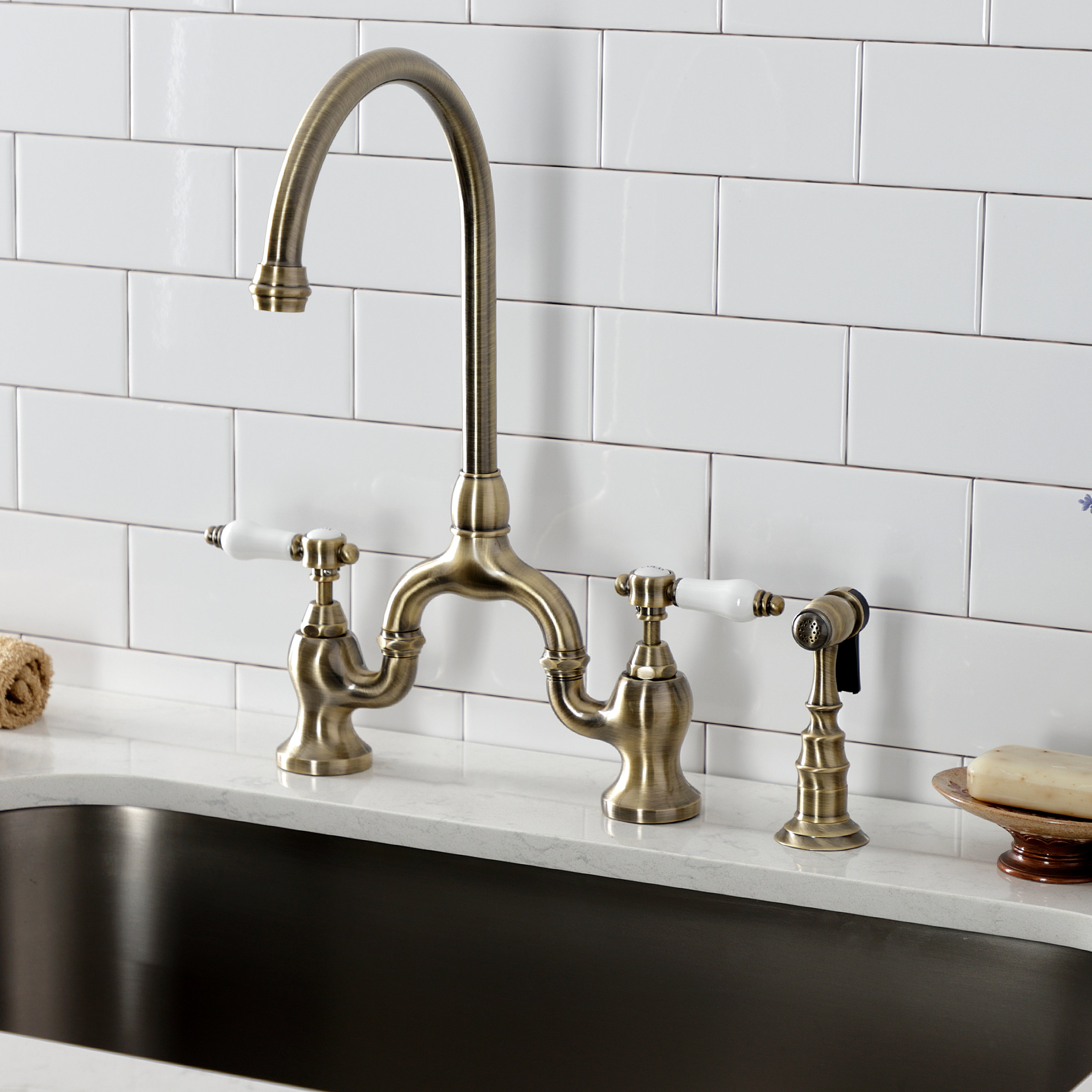 Kingston KS7793BPLBS Bel-Air Bridge Kitchen Faucet with Brass Sprayer, Antique Brass in a kitchen setting.
