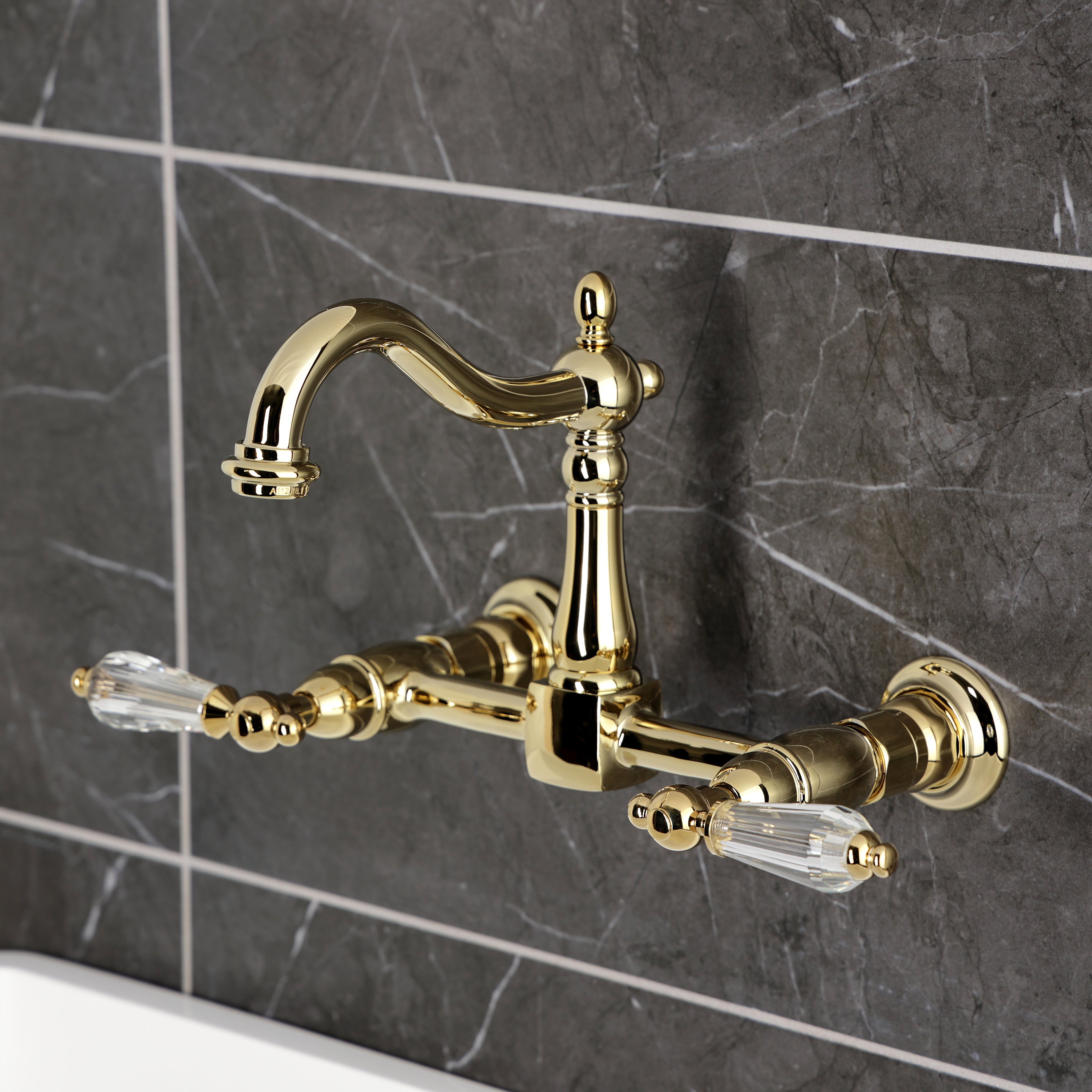 Kingston KS1263WLL Willshire Two-Handle Wall Mount Bridge Kitchen Faucet, Antique Brass on grey tiled wall.