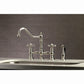 Kingston KS3277AXBS Restoration Bridge Kitchen Faucet with Brass Sprayer, Brushed Brass in a stylish kitchen setting.
