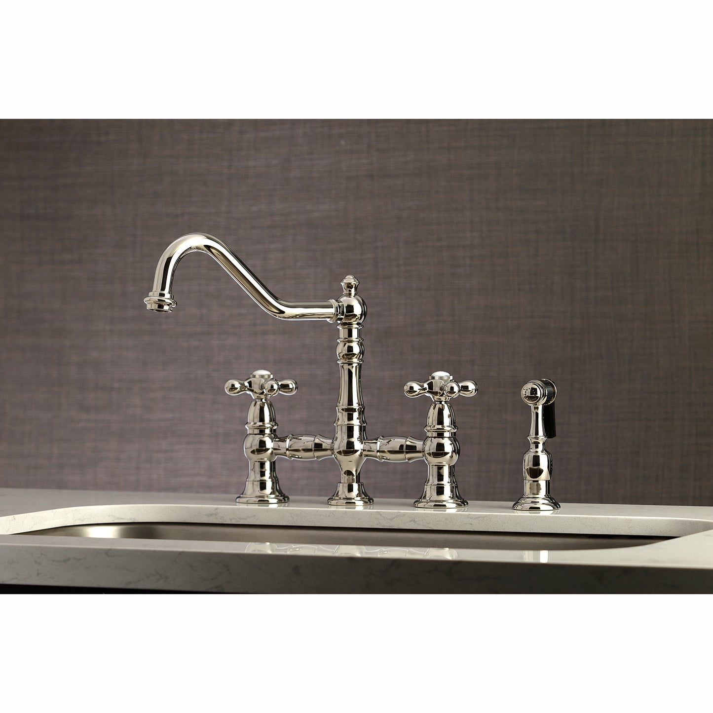 Kingston KS3277AXBS Restoration Bridge Kitchen Faucet with Brass Sprayer, Brushed Brass in a stylish kitchen setting.