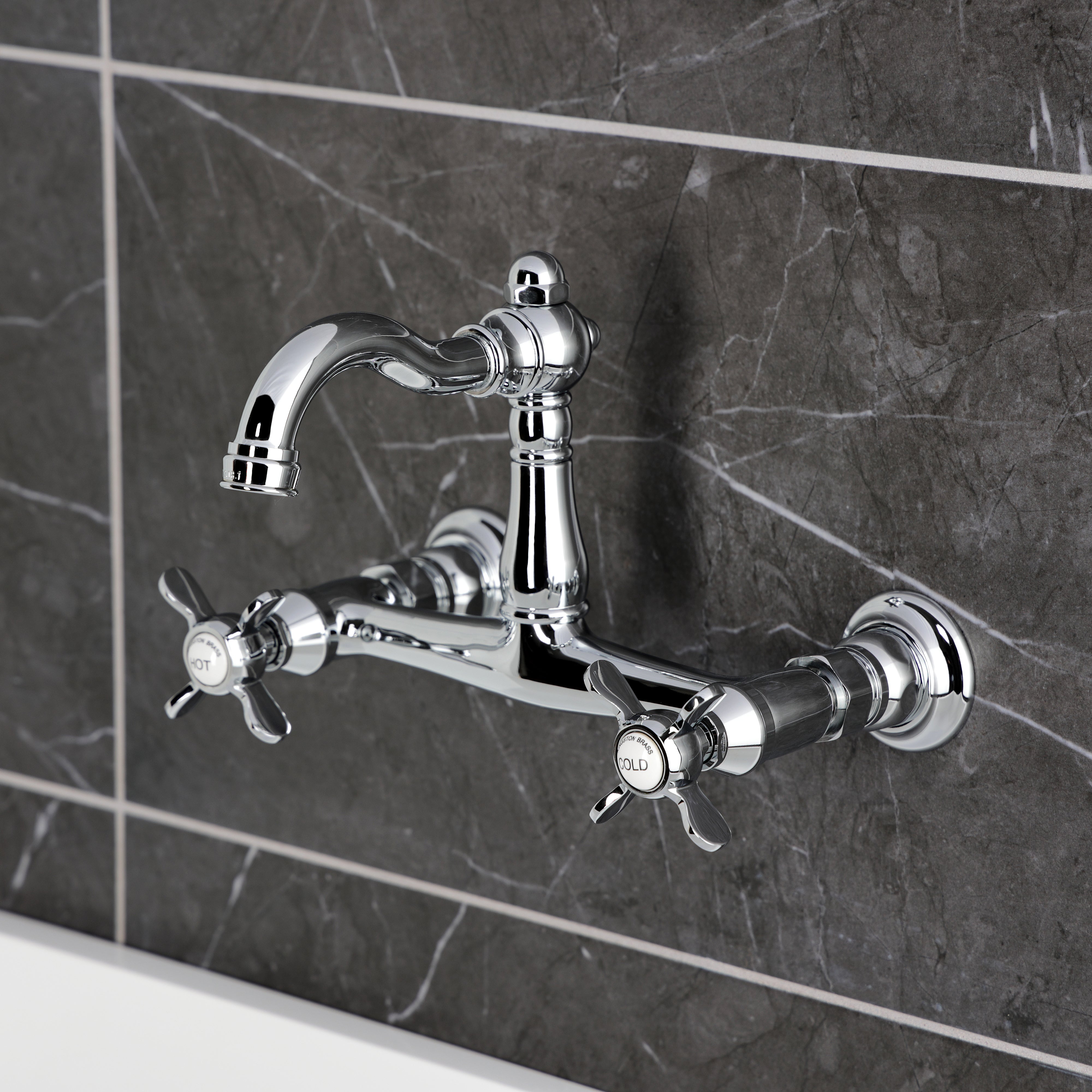 Kingston KS3253BEX Essex Two-Handle Wall Mount Bridge Kitchen Faucet, Antique Brass on a modern tiled wall.