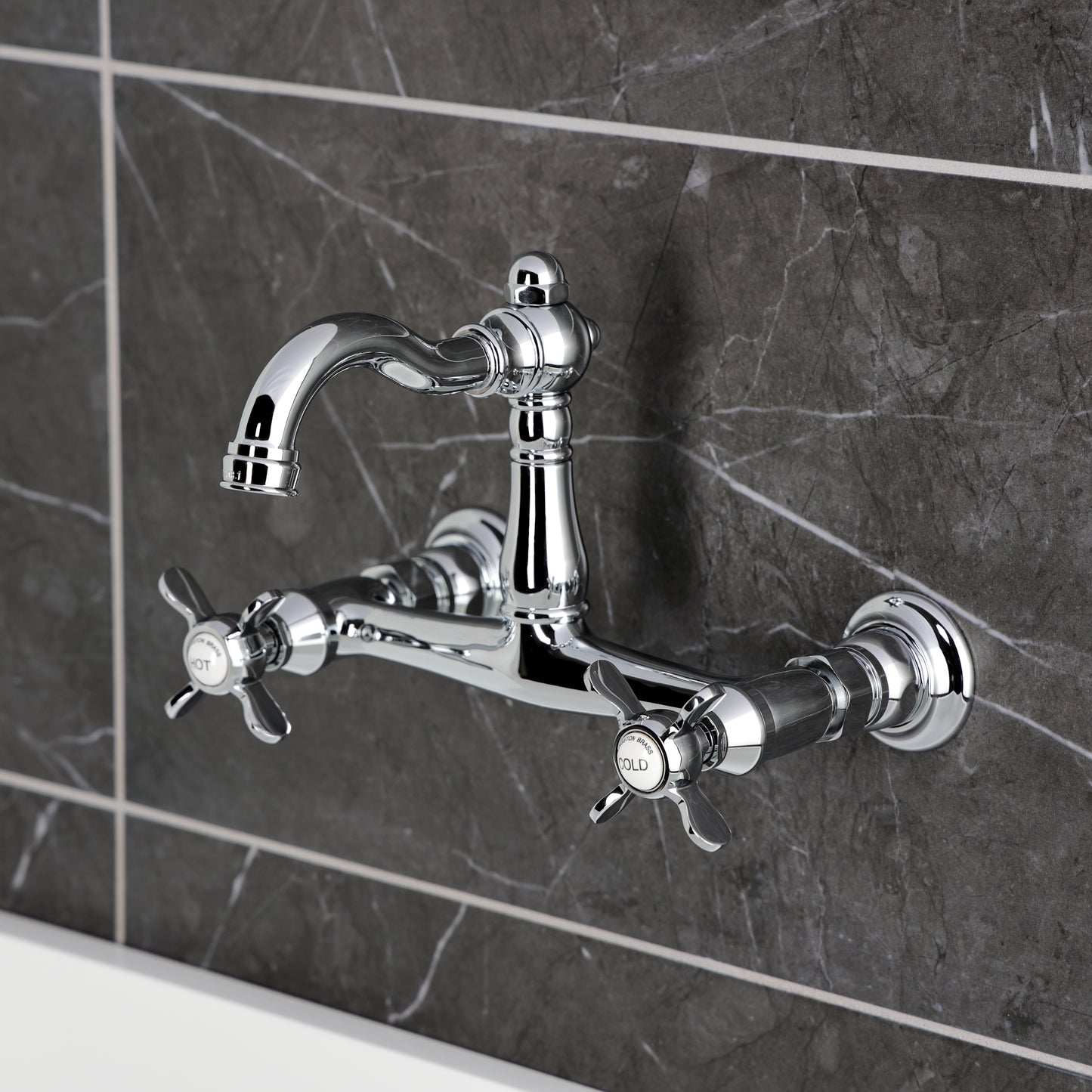 Kingston KS3253BEX Essex Two-Handle Wall Mount Bridge Kitchen Faucet, Antique Brass on a modern tiled wall.