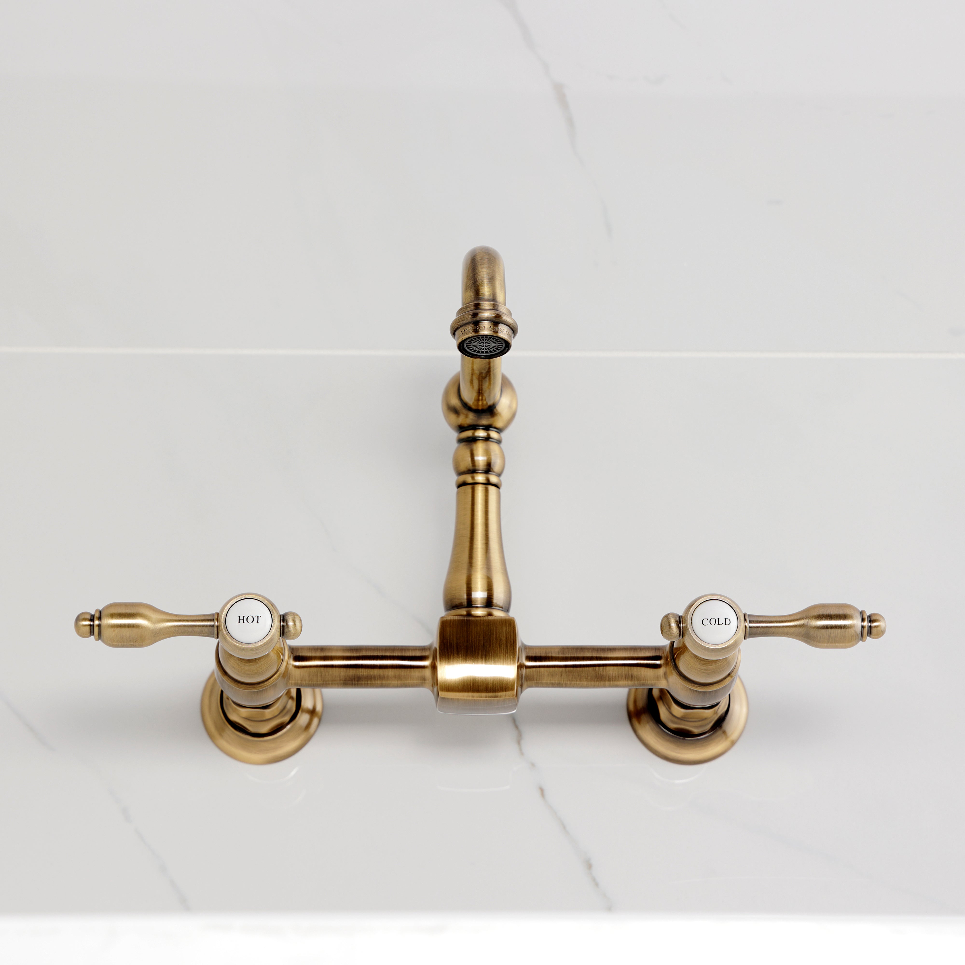 Kingston KS2443TAL Tudor Two-Handle Wall Mount Bridge Kitchen Faucet, Antique Brass on marble countertop