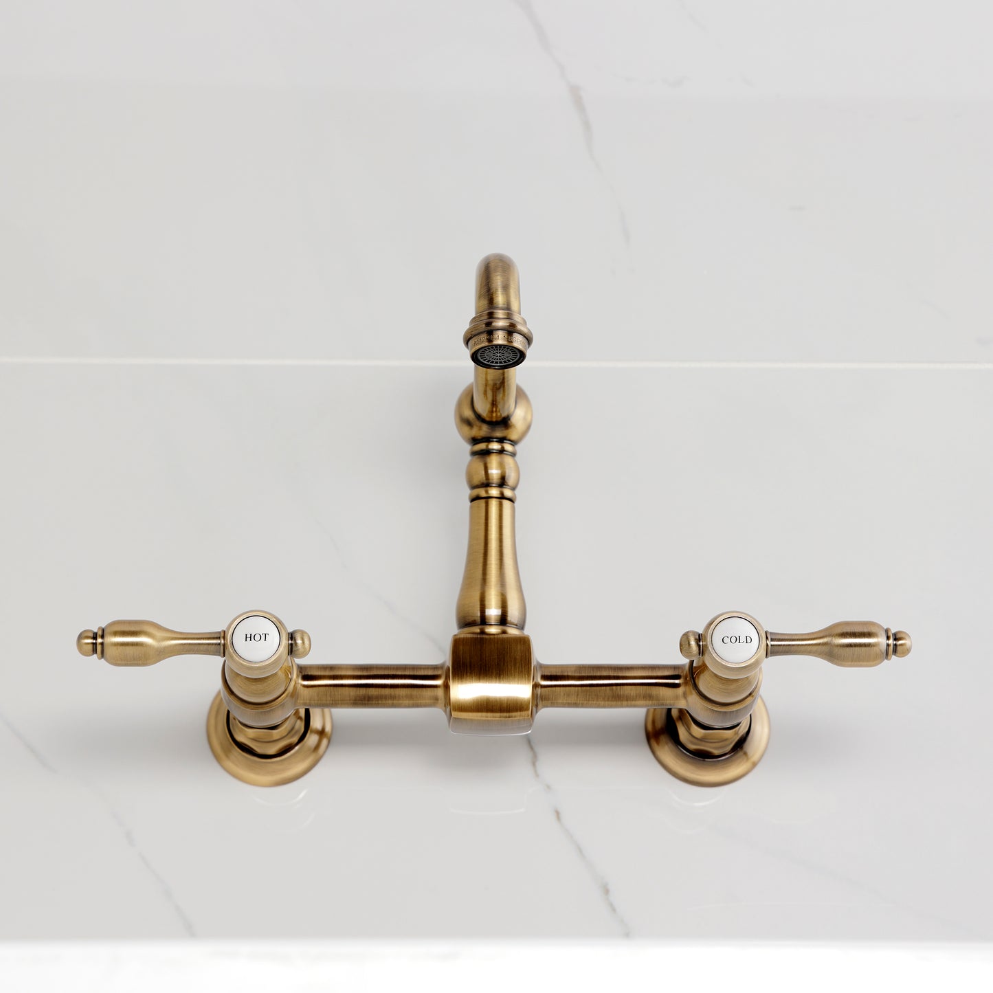 Kingston KS2443TAL Tudor Two-Handle Wall Mount Bridge Kitchen Faucet, Antique Brass on marble countertop