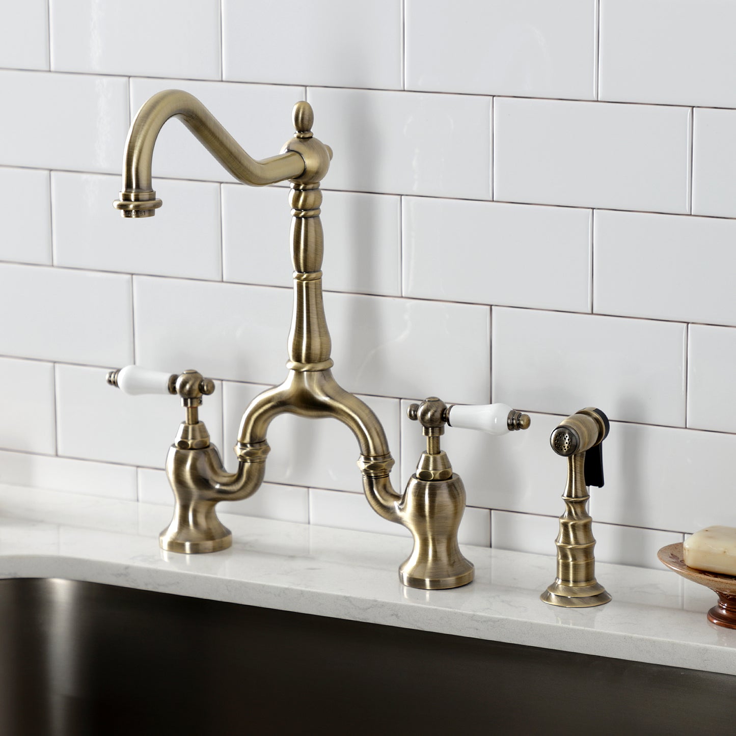 Kingston KS7753PLBS English Country Bridge Kitchen Faucet with Brass Sprayer, Antique Brass on marble countertop.
