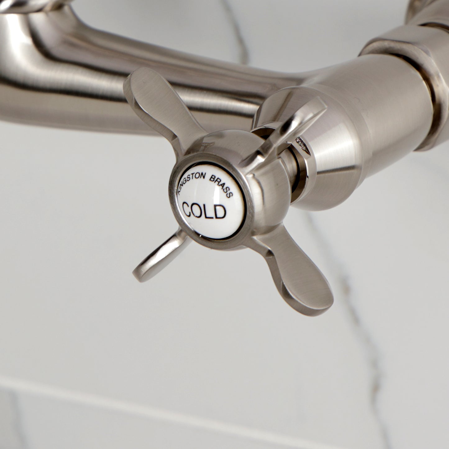Kingston KS3253BEX Essex Two-Handle Wall Mount Bridge Kitchen Faucet, Antique Brass cold water handle close-up