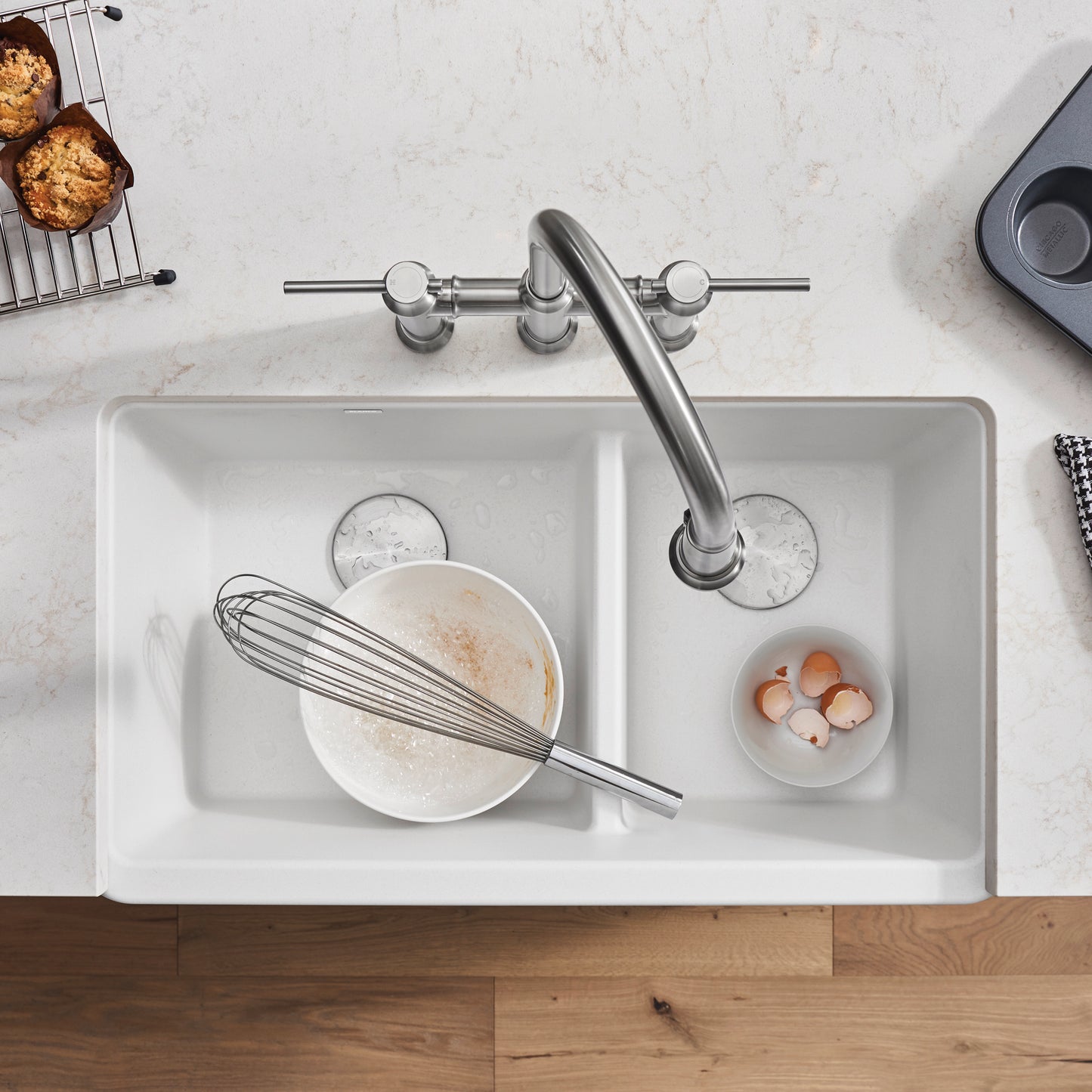 BLANCO Ikon SILGRANIT 33" Double Bowl Apron-Front Farmhouse Sink with Low Divide showcasing a whisk and bowls.