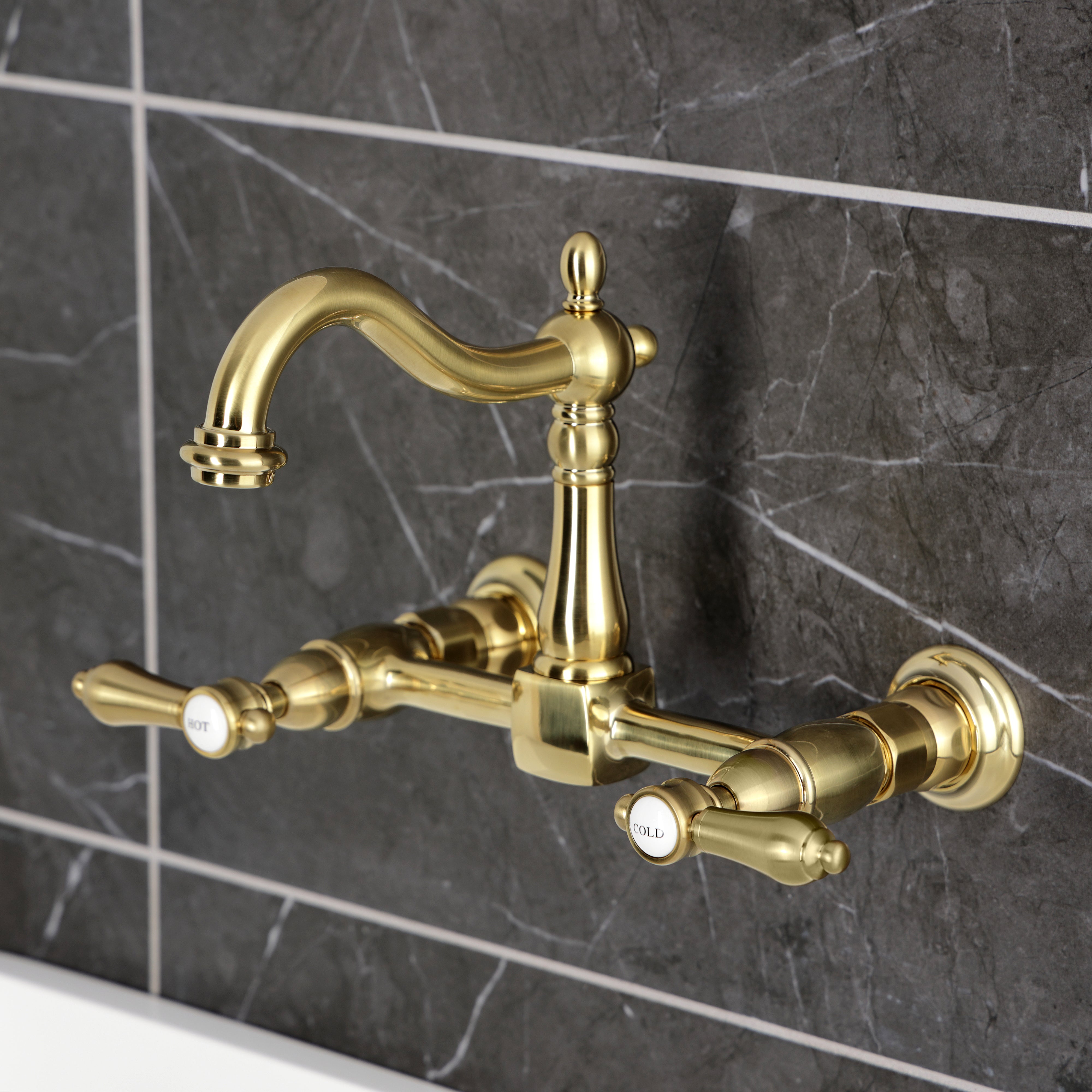 Kingston KS1263BAL Heirloom Two-Handle Wall Mount Bridge Kitchen Faucet, Antique Brass on a marble background