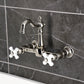 Kingston KS2443PX Heritage Two-Handle Wall Mount Bridge Kitchen Faucet, Antique Brass with white porcelain cross handles.
