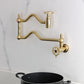 Kingston Brass KS2107CG Fuller Wall Mount Pot Filler Faucet, Brushed Brass mounted above a pot on a countertop.