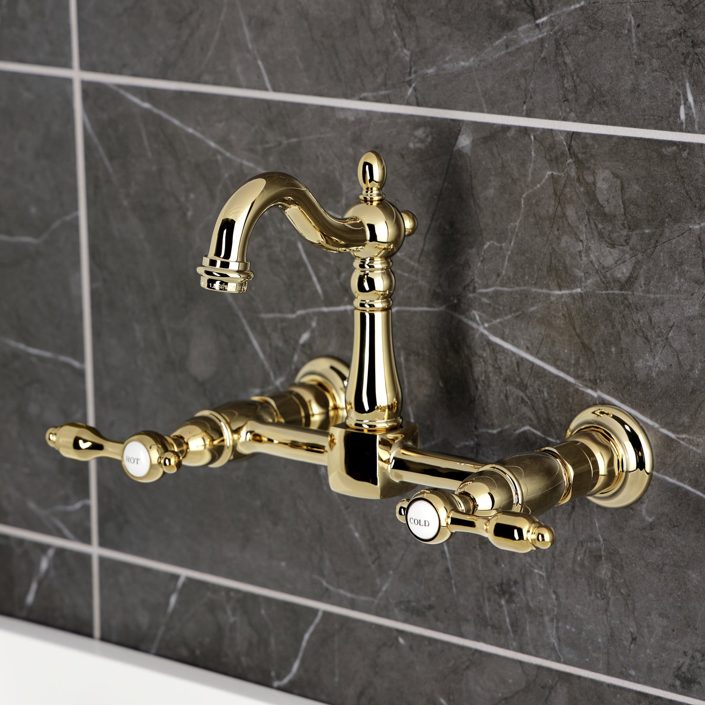Kingston KS2443TAL Tudor Two-Handle Wall Mount Bridge Kitchen Faucet, Antique Brass in a luxurious design against a marble backdrop.