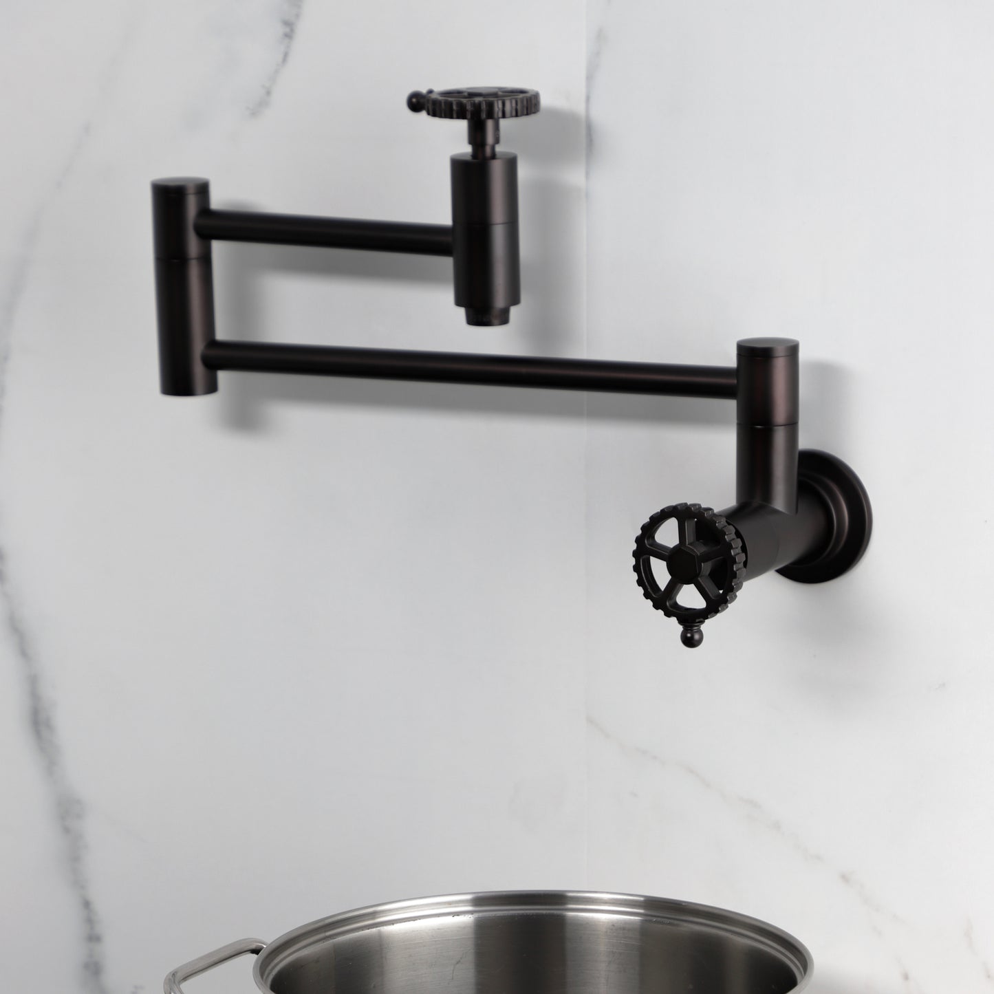 Kingston Brass KS8103CG Fuller Wall Mount Pot Filler Faucet, Antique Brass against a marble backdrop.