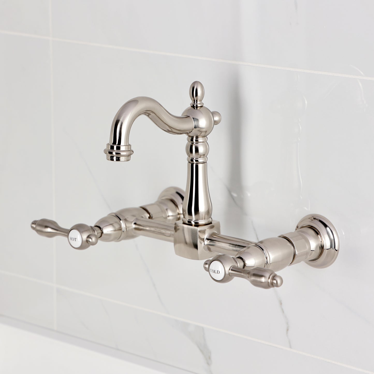 Kingston KS2443TAL Tudor Two-Handle Wall Mount Bridge Kitchen Faucet, Antique Brass on a modern backsplash.