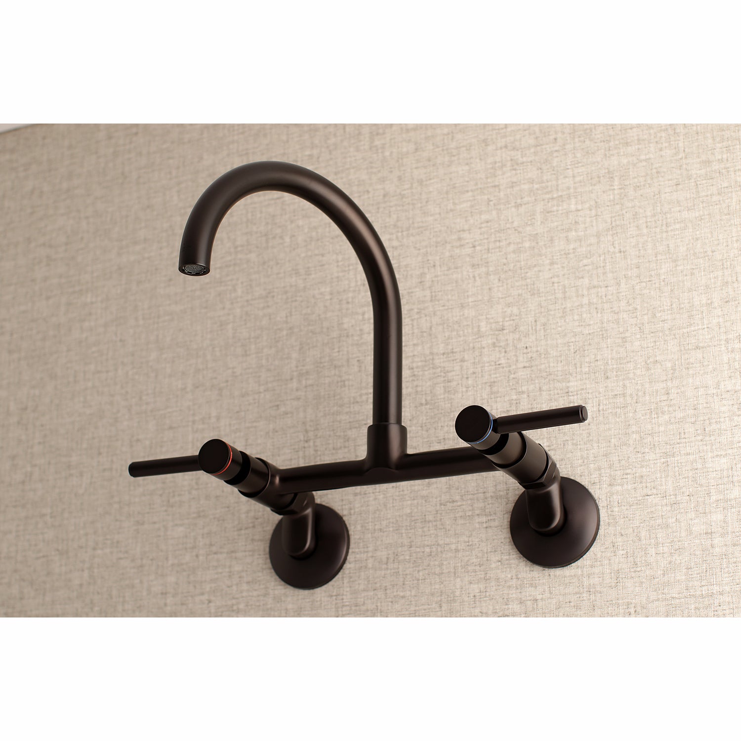 Kingston Brass KS814SB Concord Wall Mount Bridge Kitchen Faucet in a modern gooseneck design against a textured background.
