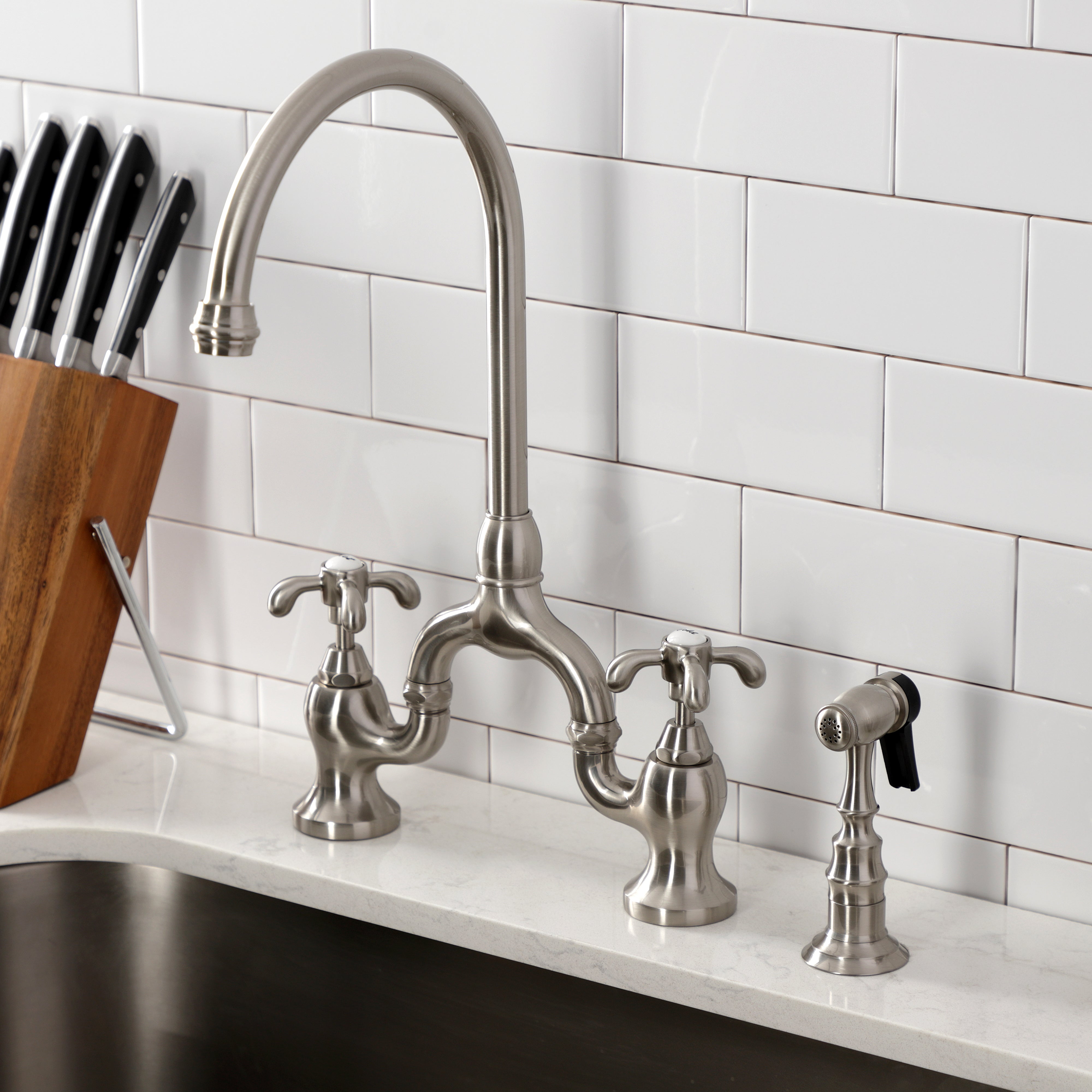 Kingston KS7793TXBS French Country Bridge Kitchen Faucet with Brass Sprayer, Antique Brass in a modern kitchen setting.