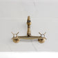 Kingston KS3253BEX Essex Two-Handle Wall Mount Bridge Kitchen Faucet, Antique Brass on a marble countertop.