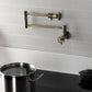Kingston Brass KS4103RKX Webb Wall Mount Pot Filler Faucet with Knurled Handle, Antique Brass on a modern kitchen backsplash.