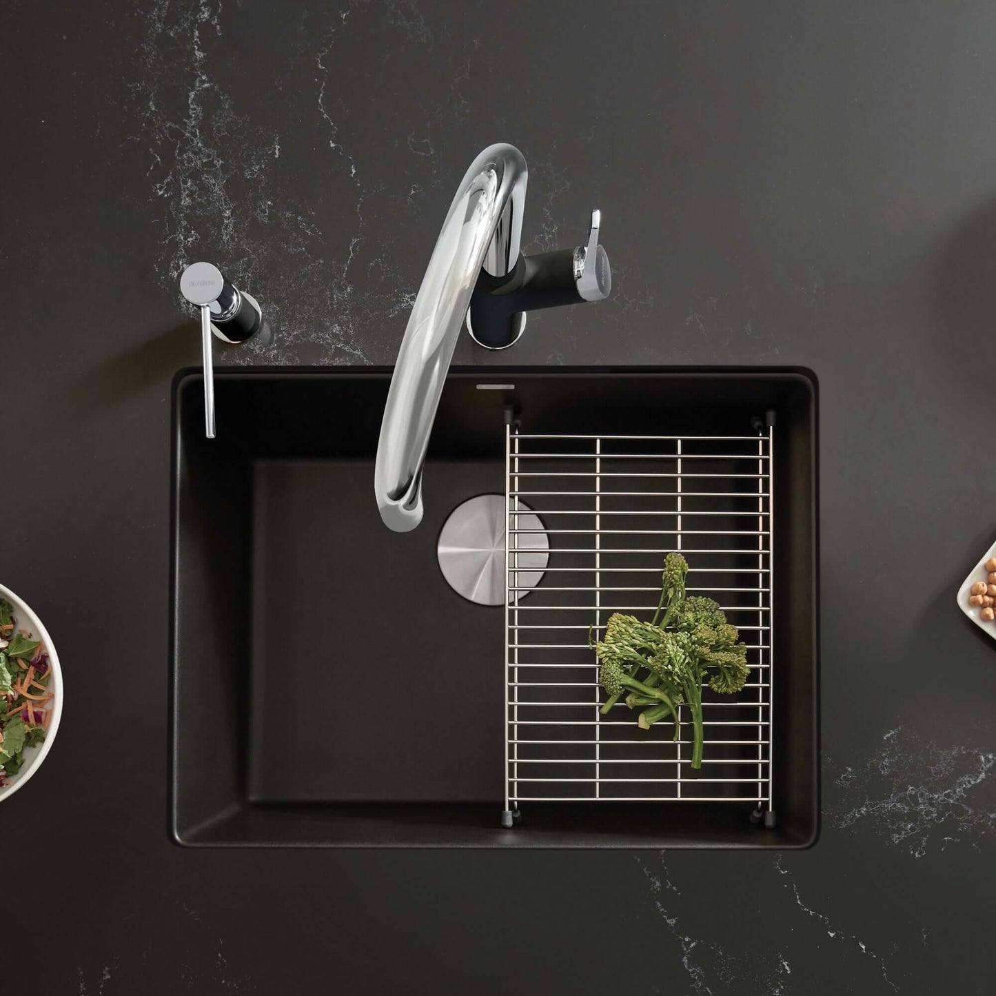 BLANCO PRECIS 24" SILGRANIT Compact Undermount Sink with vegetable on rack and modern faucet on dark surface.