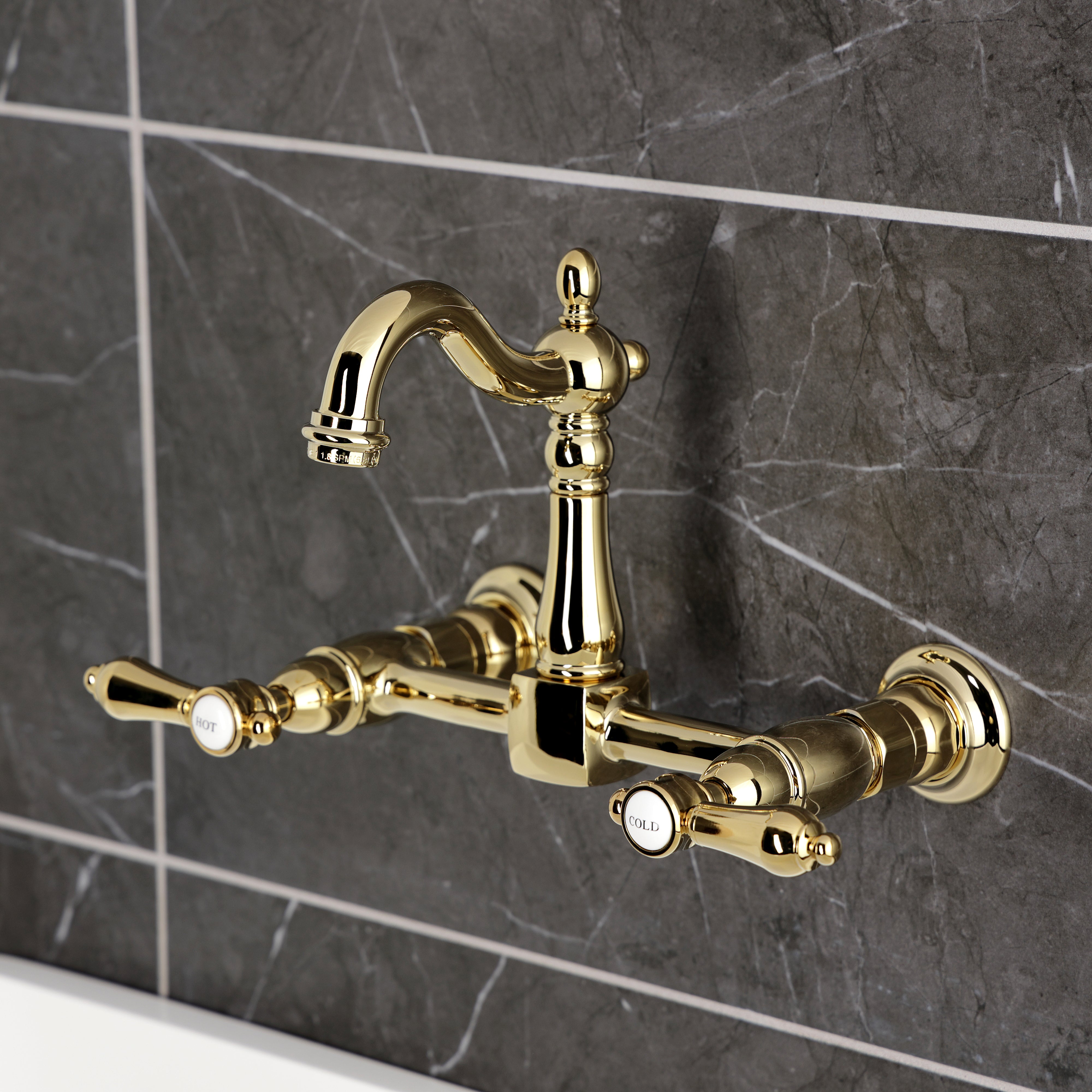 Kingston KS2443BAL Heirloom Two-Handle Wall Mount Bridge Kitchen Faucet, Antique Brass on dark tile background.