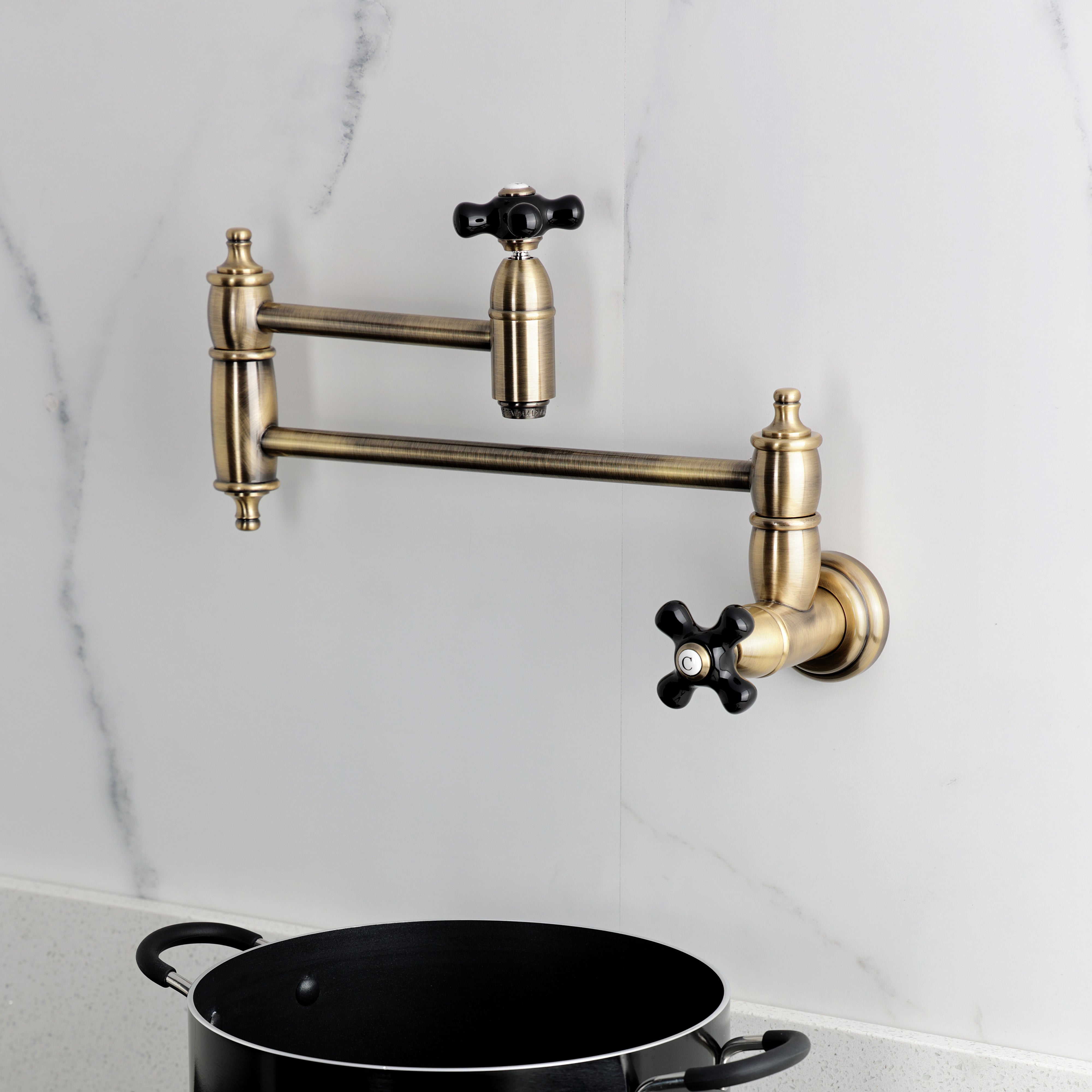 Kingston Brass KS3103PKX Duchess Wall Mount Pot Filler Faucet, Antique Brass in kitchen above pot