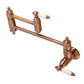 Kingston Brass KS3103PL Restoration Wall Mount Pot Filler Faucet, Antique Brass with swing arms and white ceramic handles.