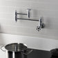 Kingston Brass KS3103RKZ Wendell Wall Mount Pot Filler Faucet with Knurled Handle, Antique Brass in a kitchen setting.