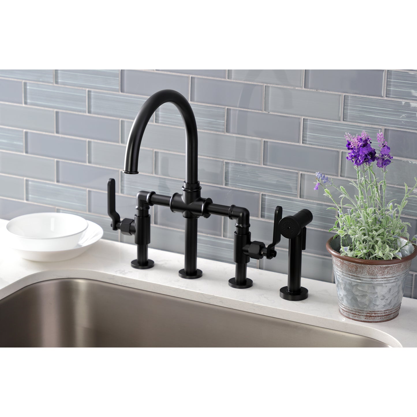 Kingston KS2333KL Whitaker Industrial Style Bridge Kitchen Faucet with Brass Sprayer, Antique Brass in modern kitchen setting.
